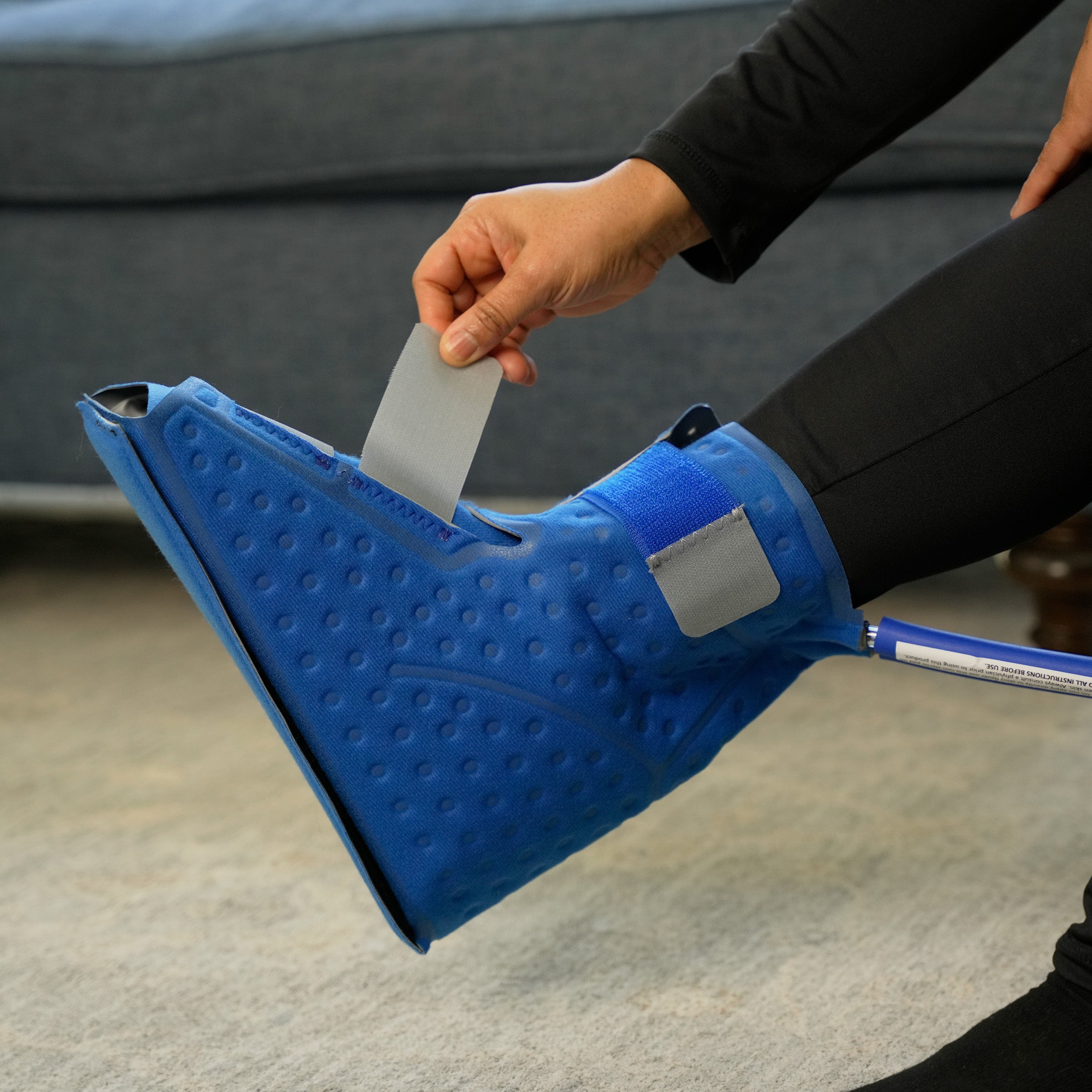 Woman applying a Upper Foot & Ankle Cold Therapy Pad on her foot in a living room setting