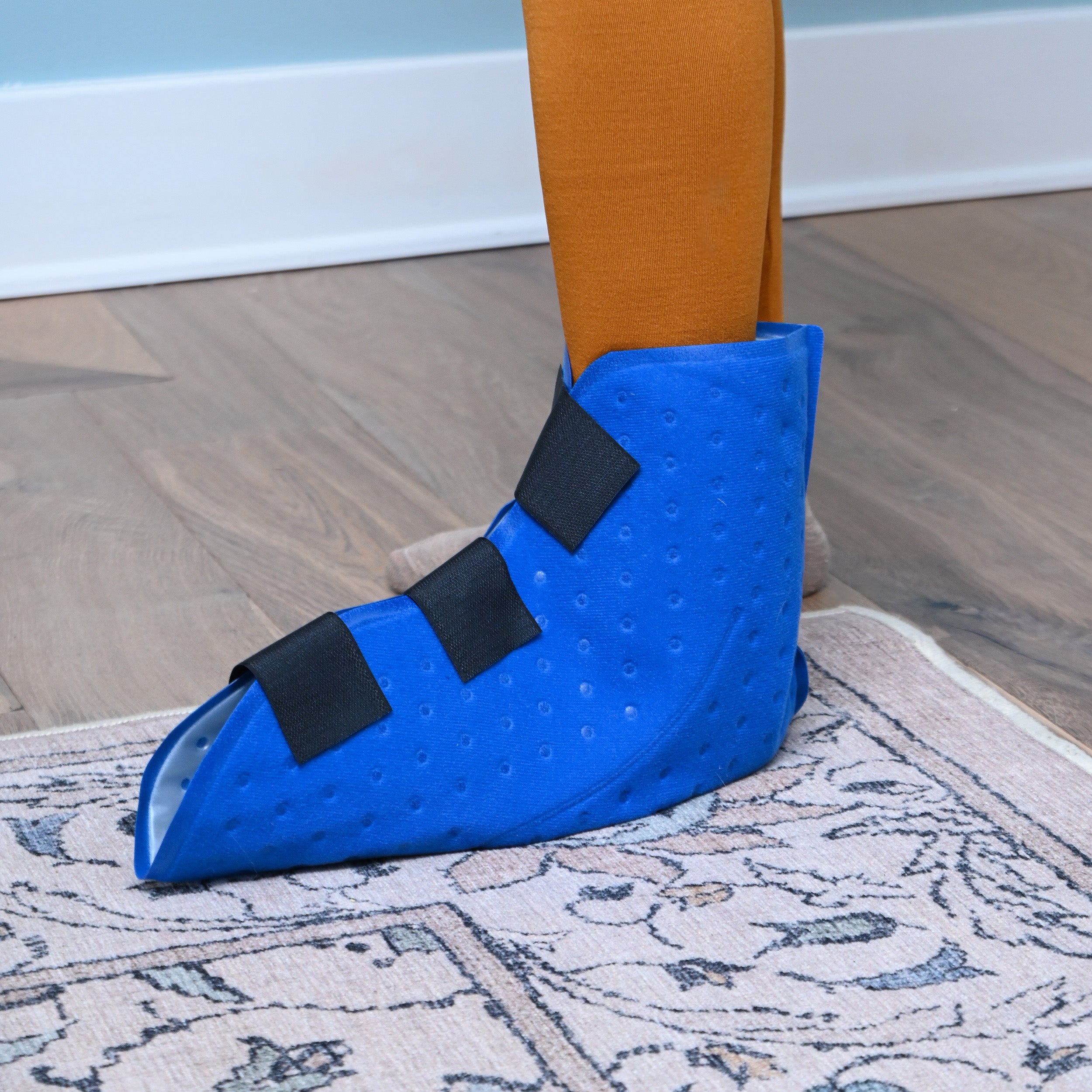 Blue Active Ice® Full Coverage Foot & Ankle Cold Therapy Pad on a person's foot, standing on a wooden floor.