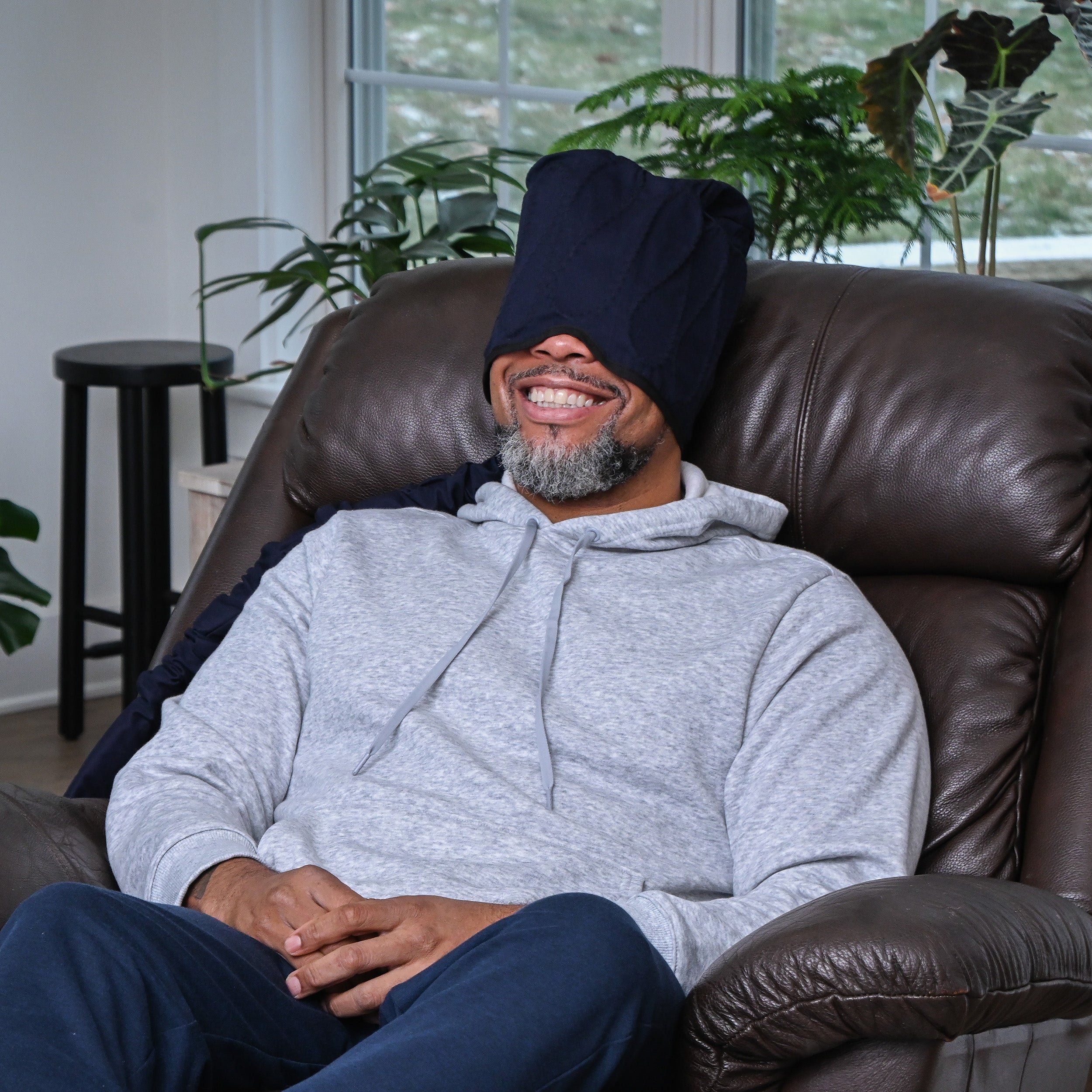 Man wearing the Polar Active Ice® 3.0 Extended Head Cold Therapy Cap (Therapy Cap Only) on his head while sitting in a brown leather recliner