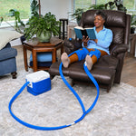 Woman sitting in a recliner with a leg elevated using a blue Active Ice® Knee & joint double 9-quart cold therapy system reading a book