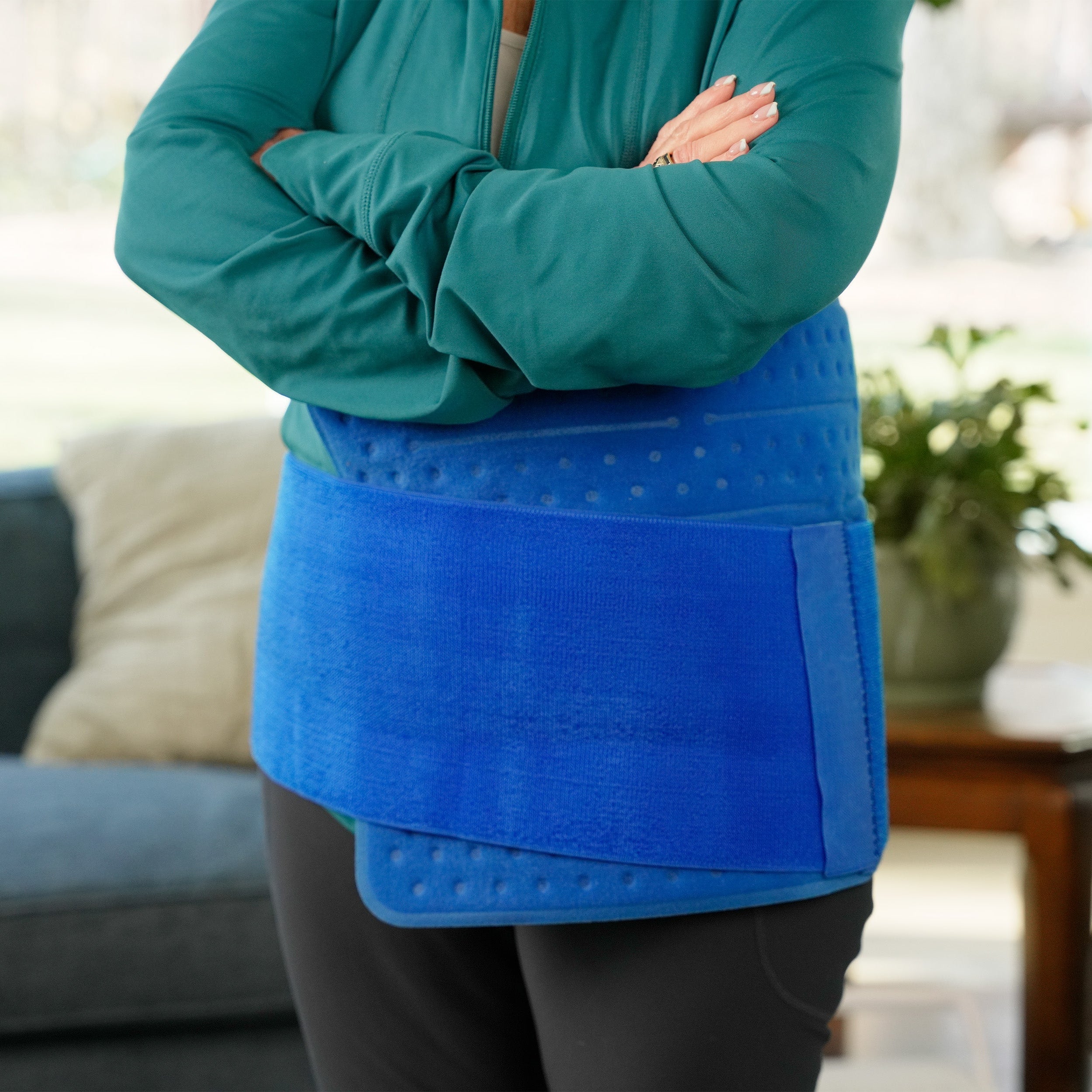 Woman wearing an Extended Coverage Back & Limb Cold Therapy Pad in a living room.