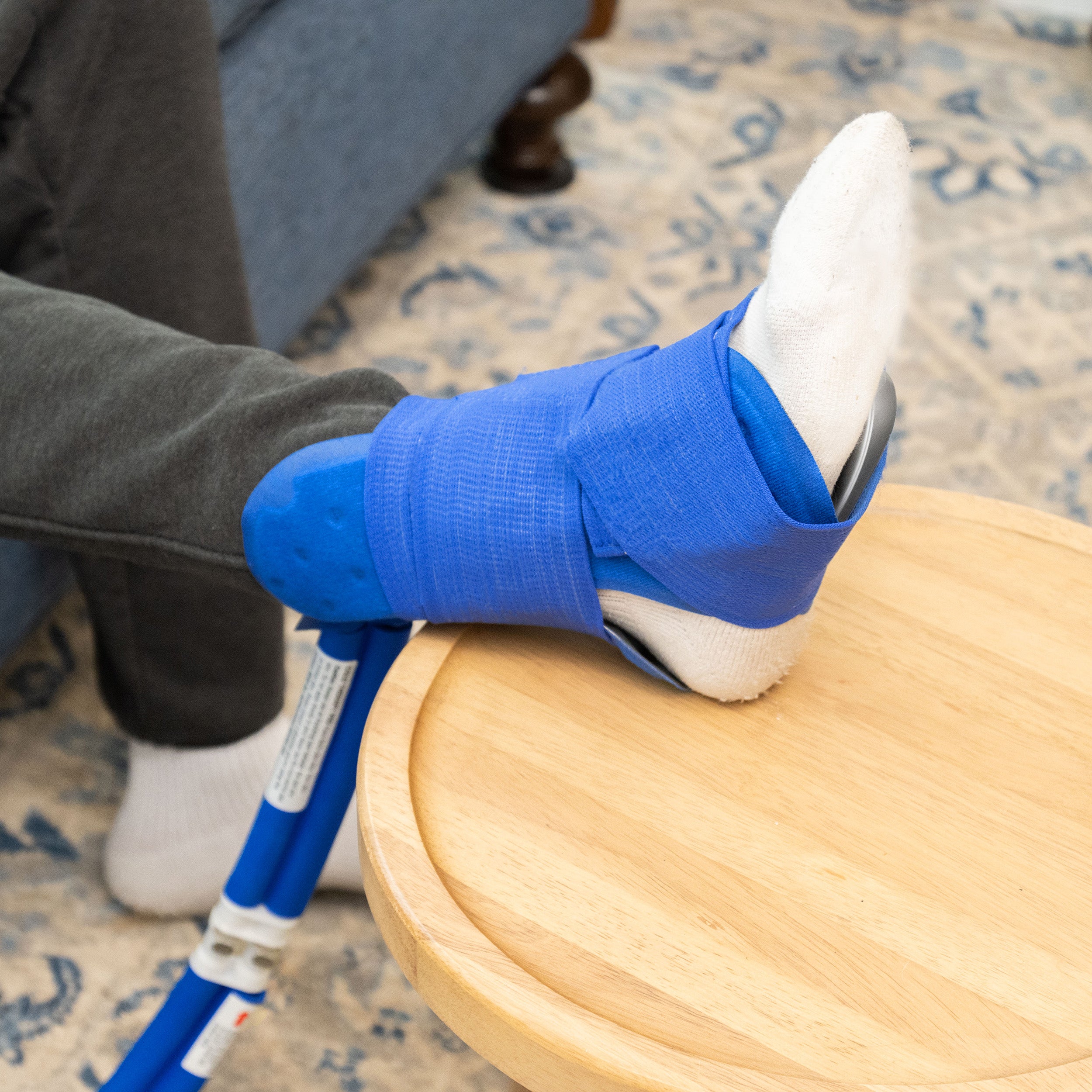 Man wearing Active Ice® Universal Cold Therapy Pad around his ankle propped up on a stool