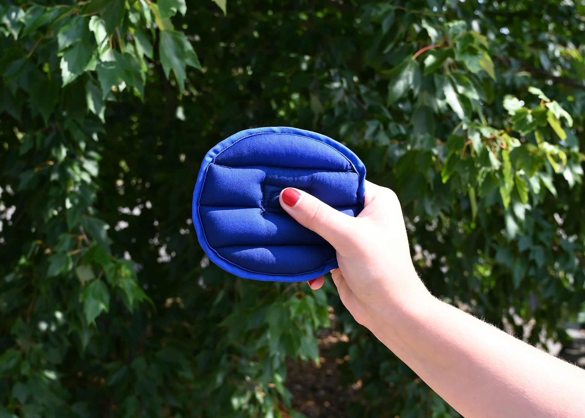 Person holding a blue Cool Comfort Crown Cooler outside after being activated in water