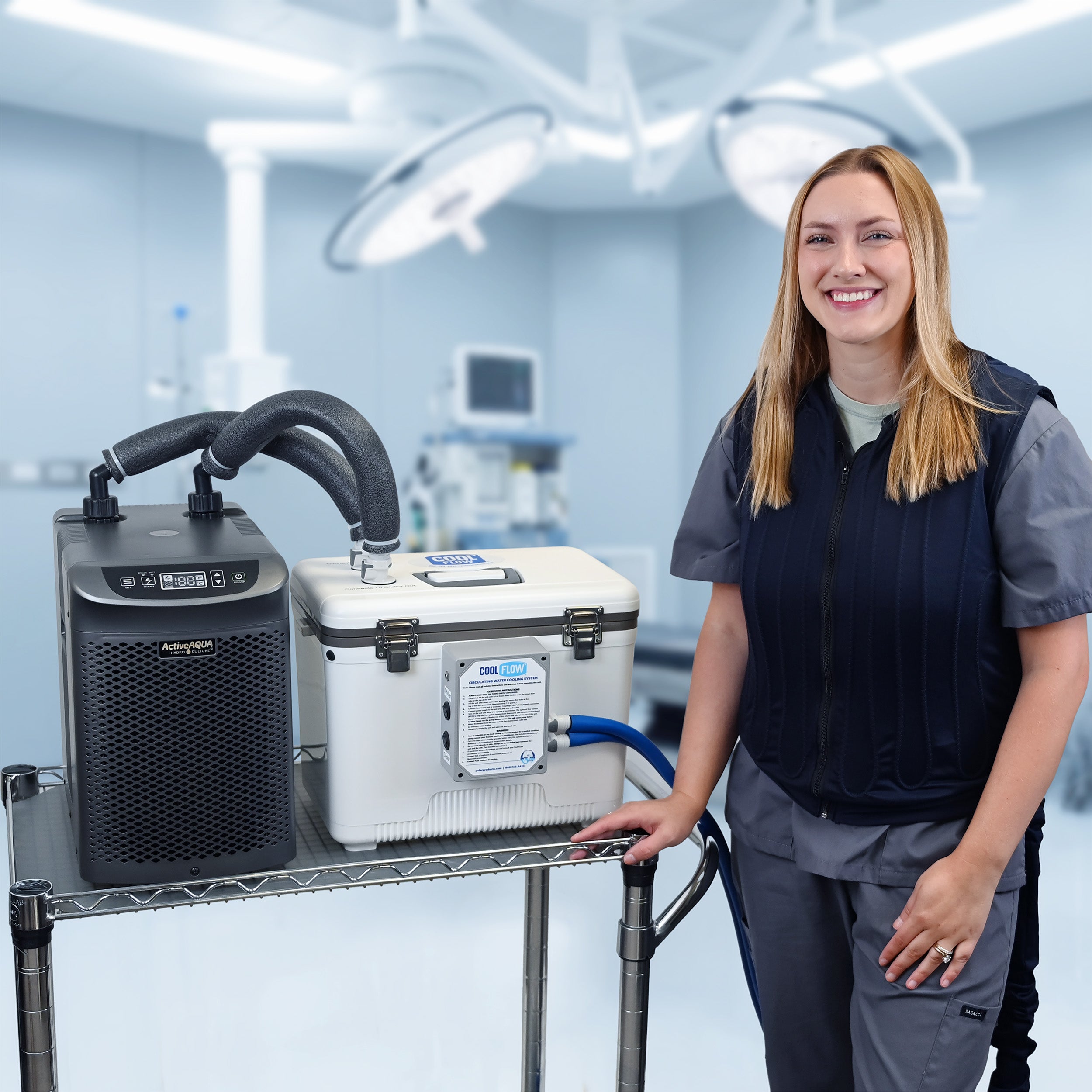 A woman in medical scrubs stands beside a metal cart holding an Arctic Chiller and 19-quart cooling reservoir in a bright operating room. She's attached to the reservoir with the fitted circulating cooling vest. The background shows surgical lights and medical equipment.