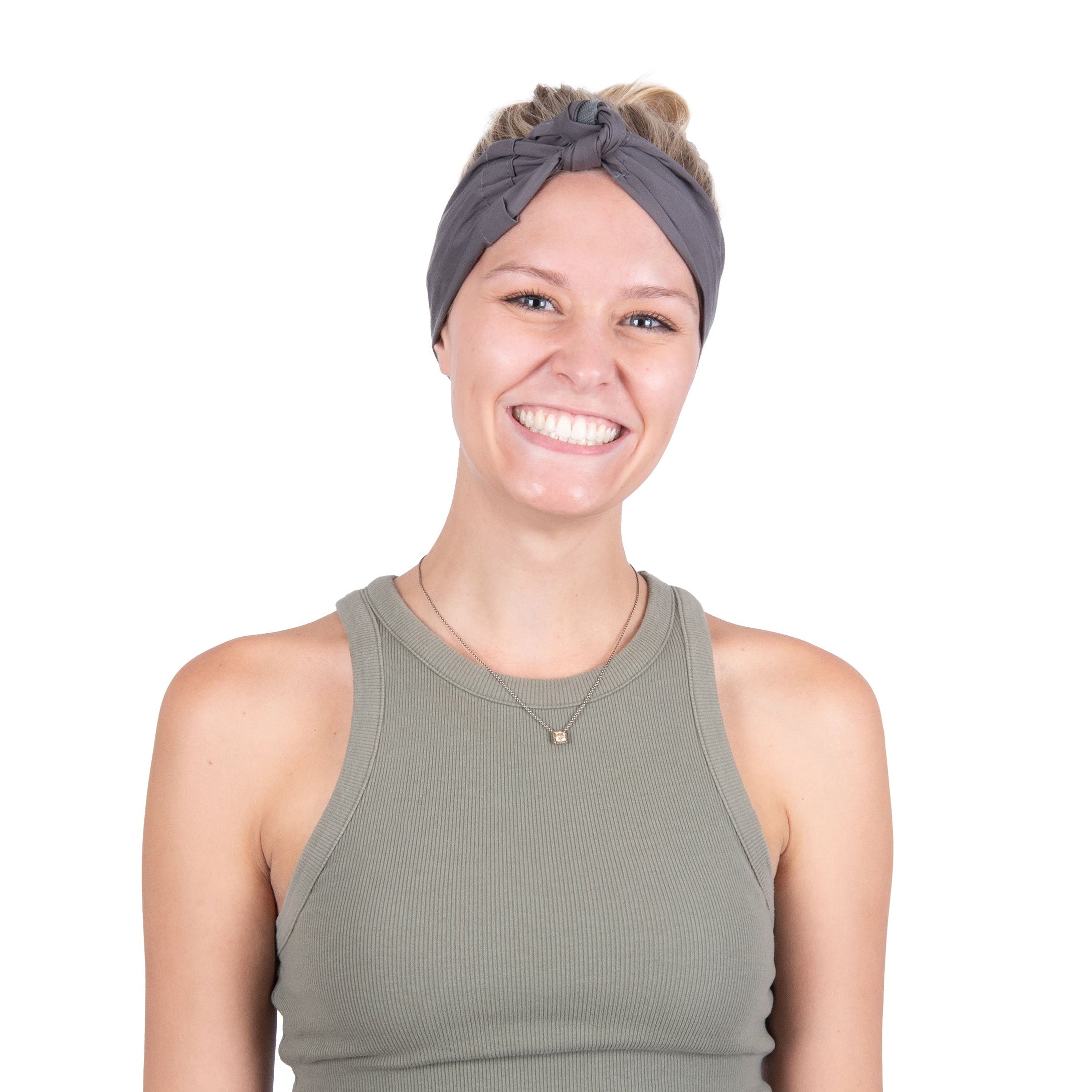 A smiling woman with her hair in a bun wearing a gray deluxe cooling head wrap and an olive green ribbed tank top, isolated on a white background.