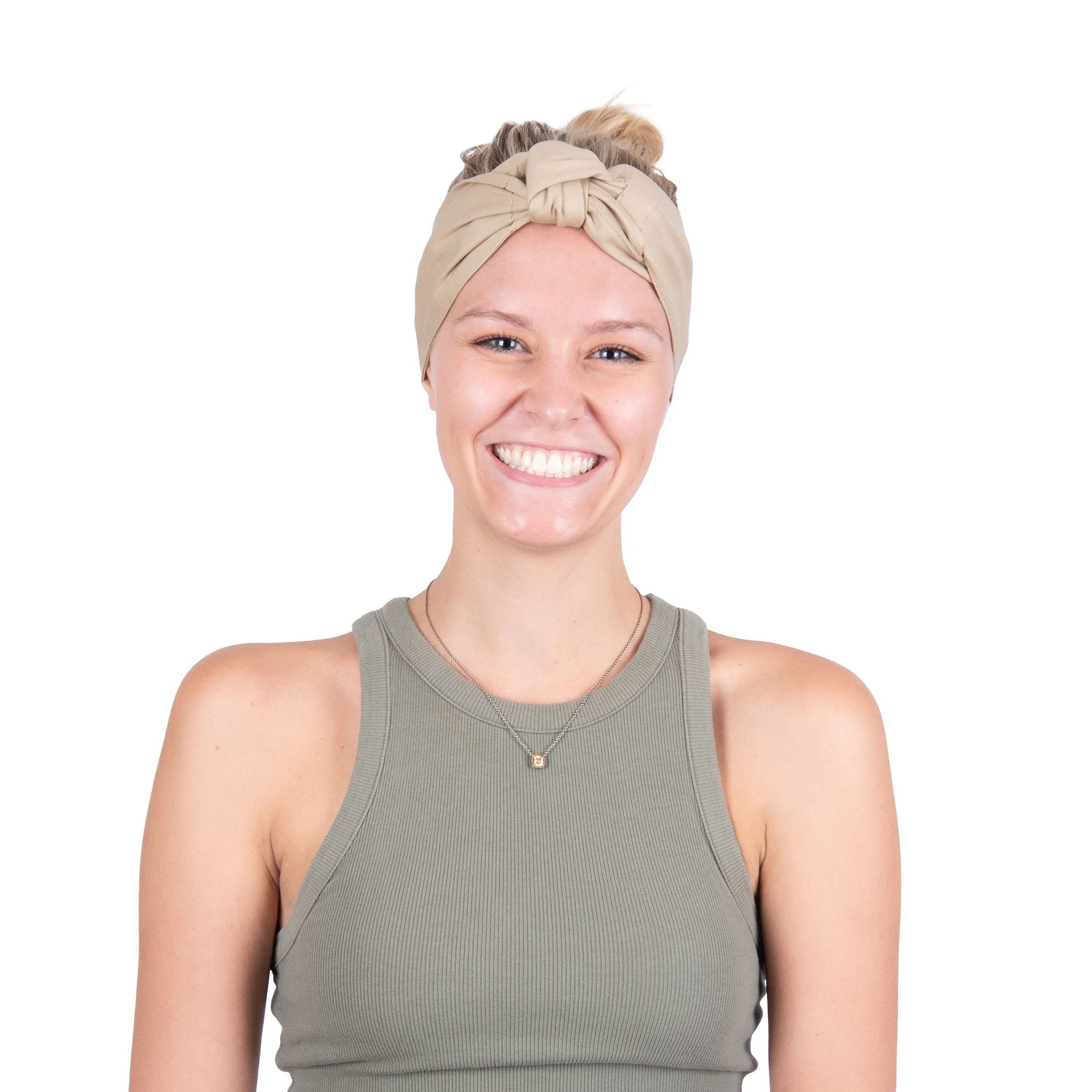 A smiling woman with blonde hair in a bun wearing a beige deluxe cooling head wrap and an olive green ribbed tank top, photographed against a solid white background.