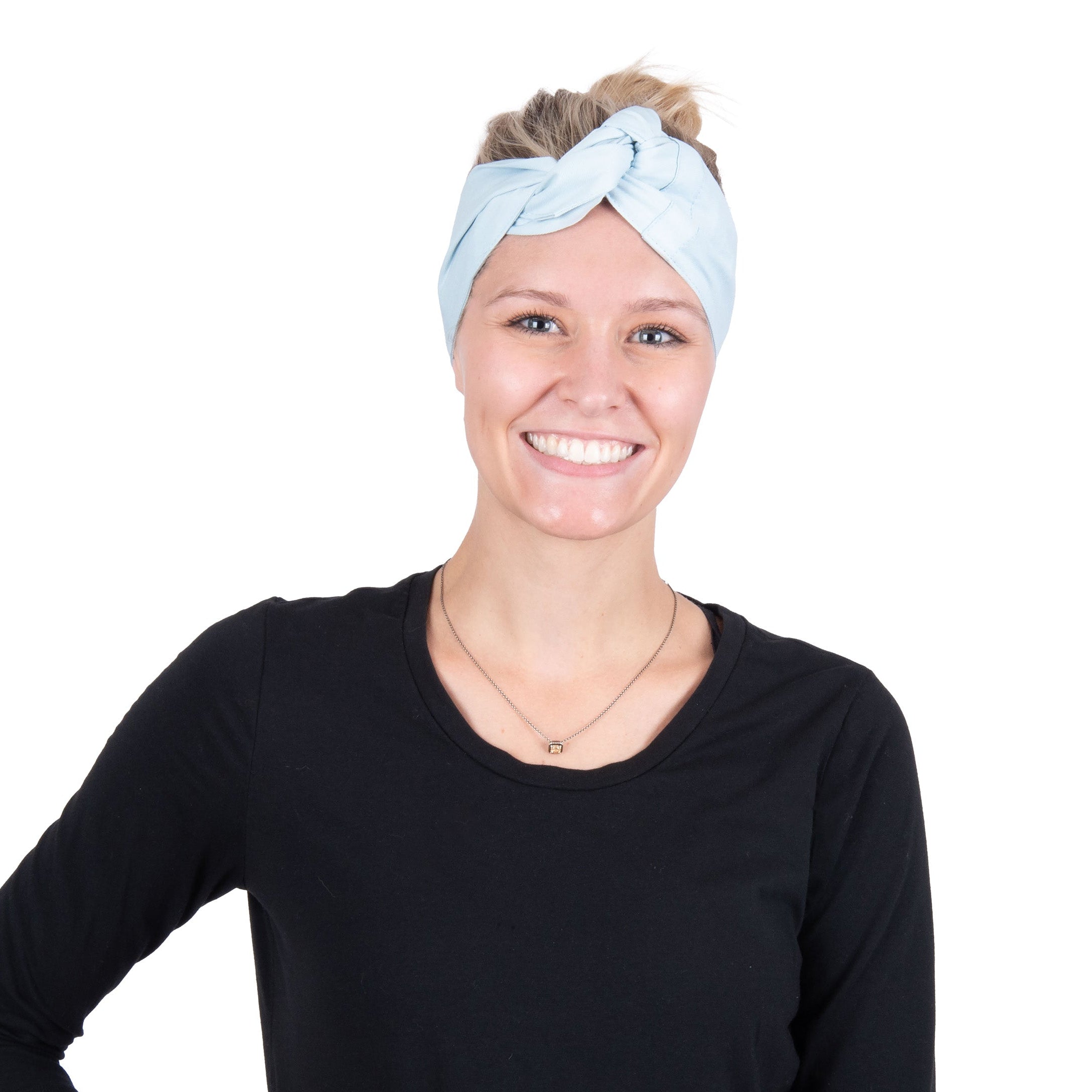 A smiling woman with blonde hair tied up in a light blue deluxe cooling head wrap, wearing a black long-sleeve top, photographed against a solid white background.