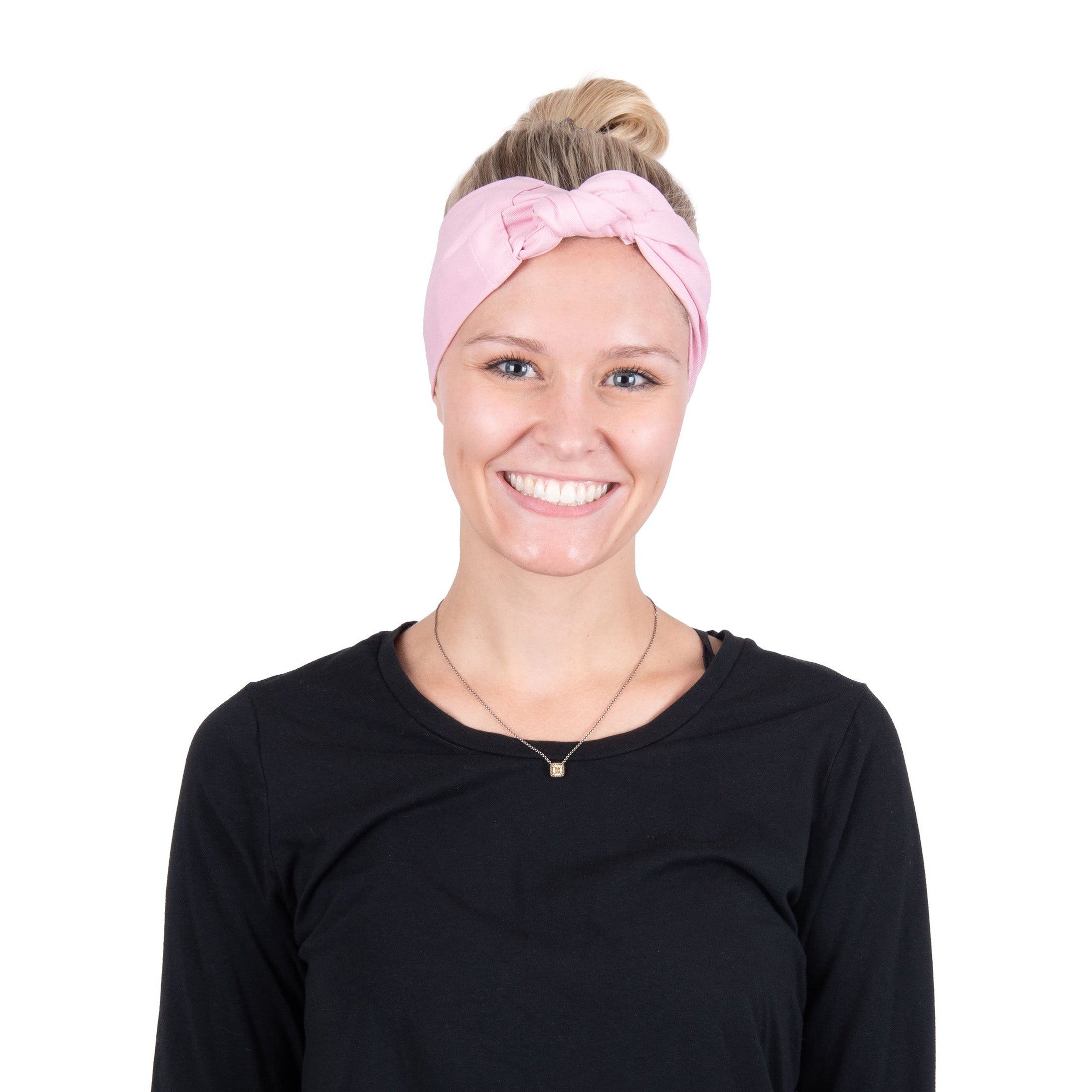 A smiling woman with blonde hair in a bun wearing a light pink deluxe cooling head wrap and a black long-sleeve top, photographed against a solid white background.