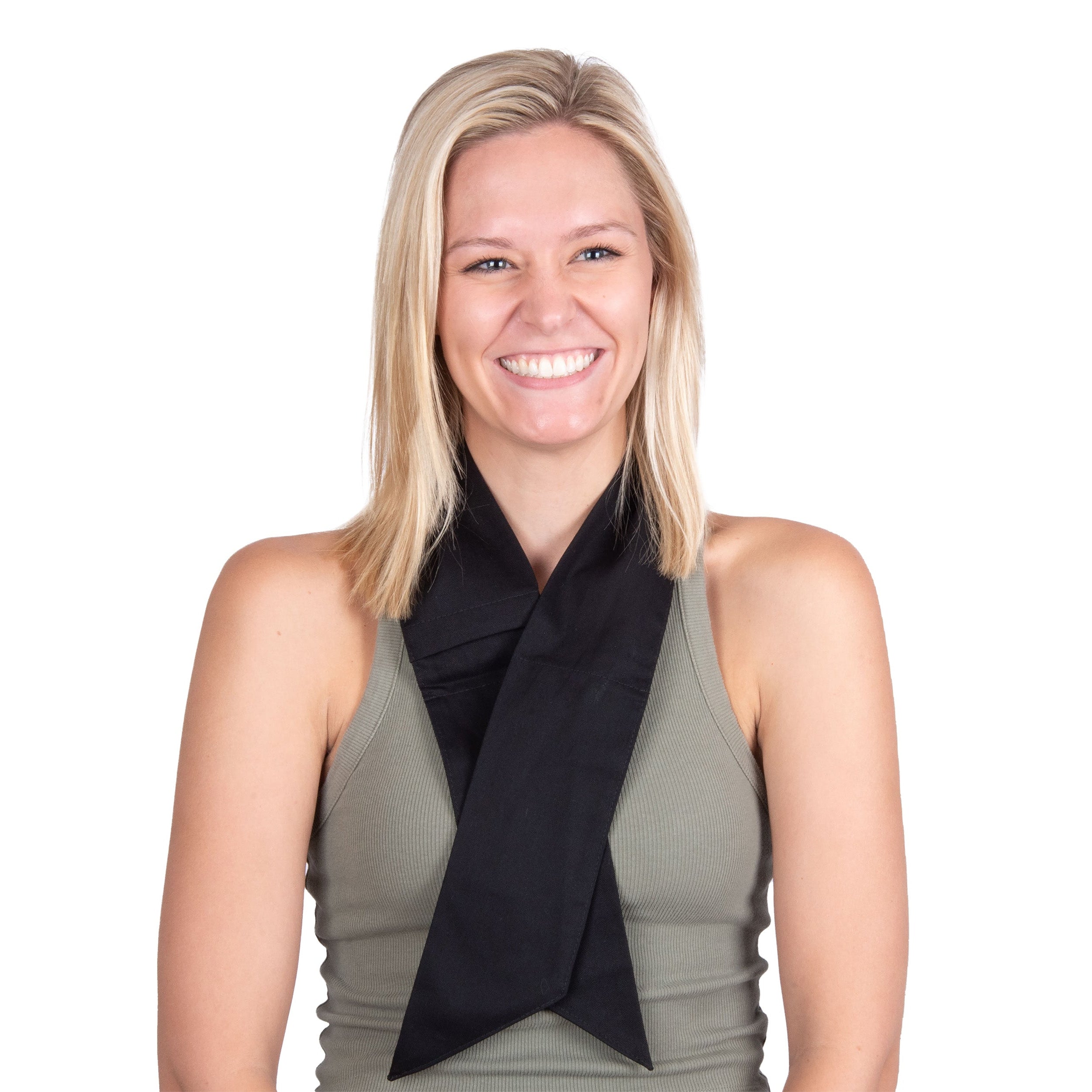 A smiling blonde woman wearing a black deluxe cooling neck wrap tied around a sage green sleeveless top, photographed against a plain white background.