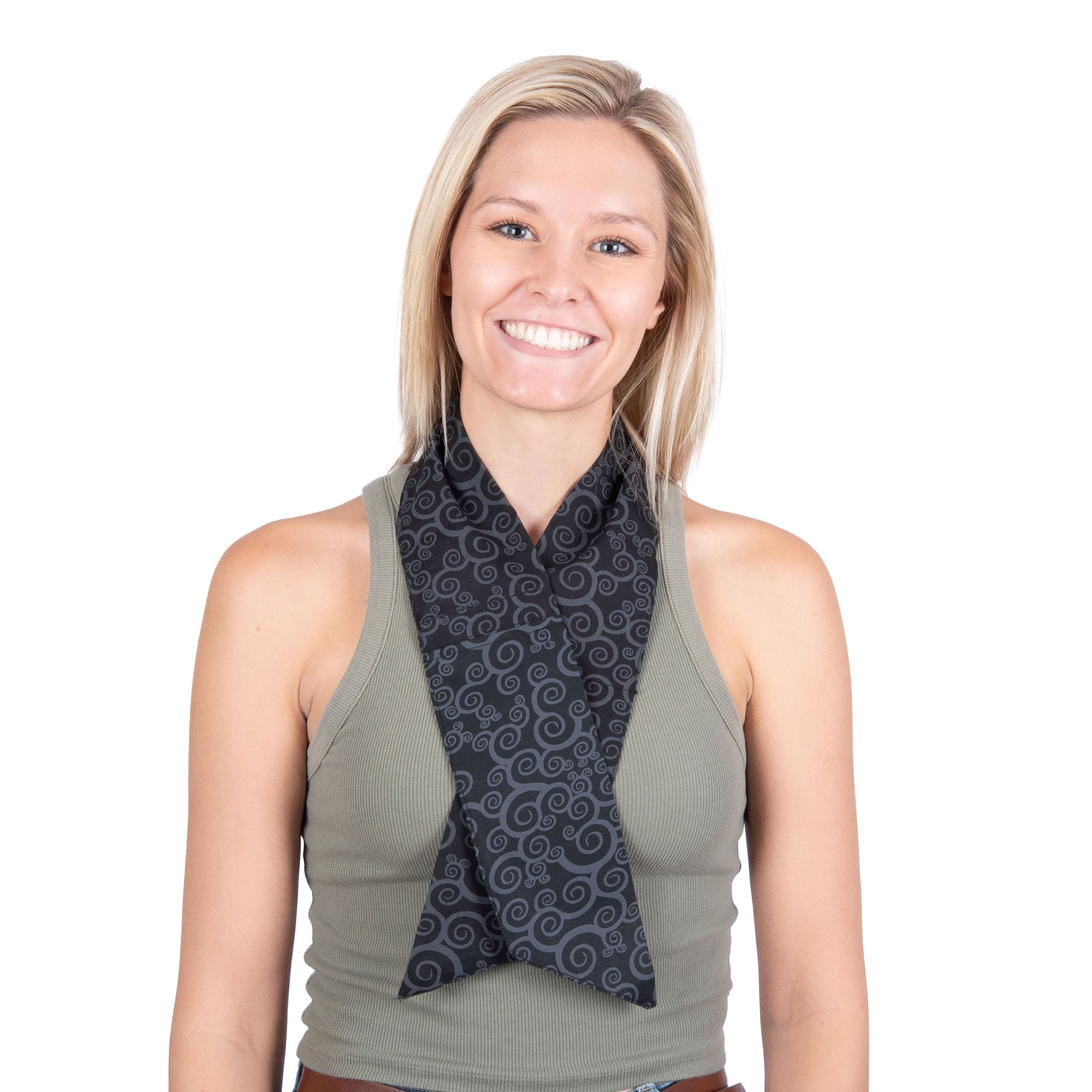 A smiling blonde woman wearing a dark black patterned cooling fashion neck scarf over an olive green tank top, shot against a solid white background.