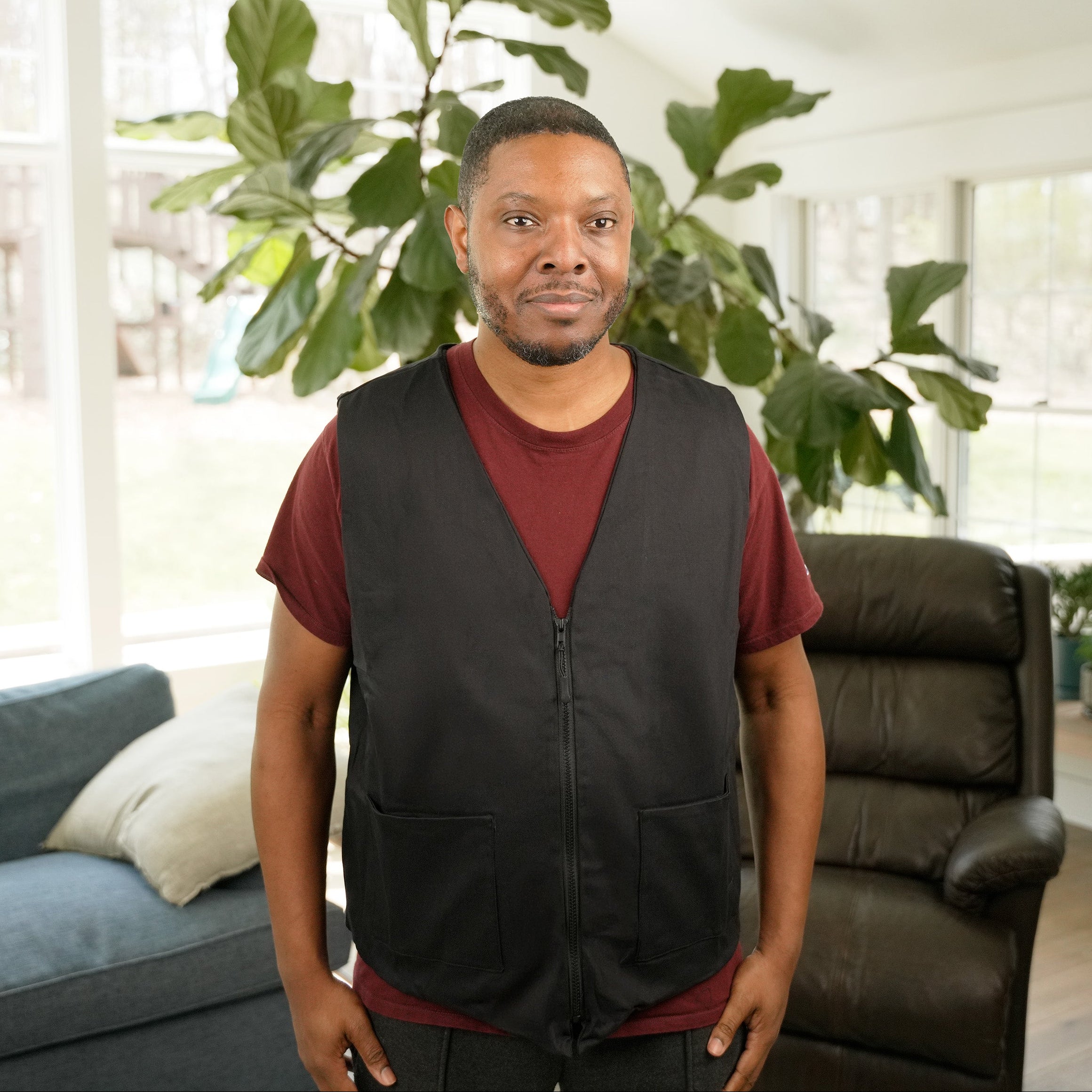 Man wearing a black Kool Max® Fashion Cooling Vest in a bright living room setting