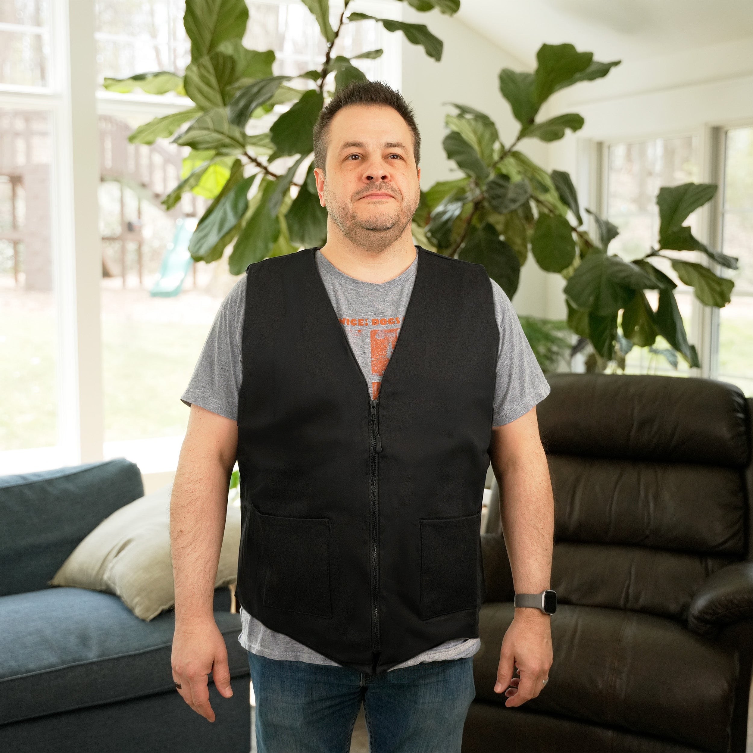 Man wearing a black Cool58® Fashion Cooling Vest in a bright living room setting