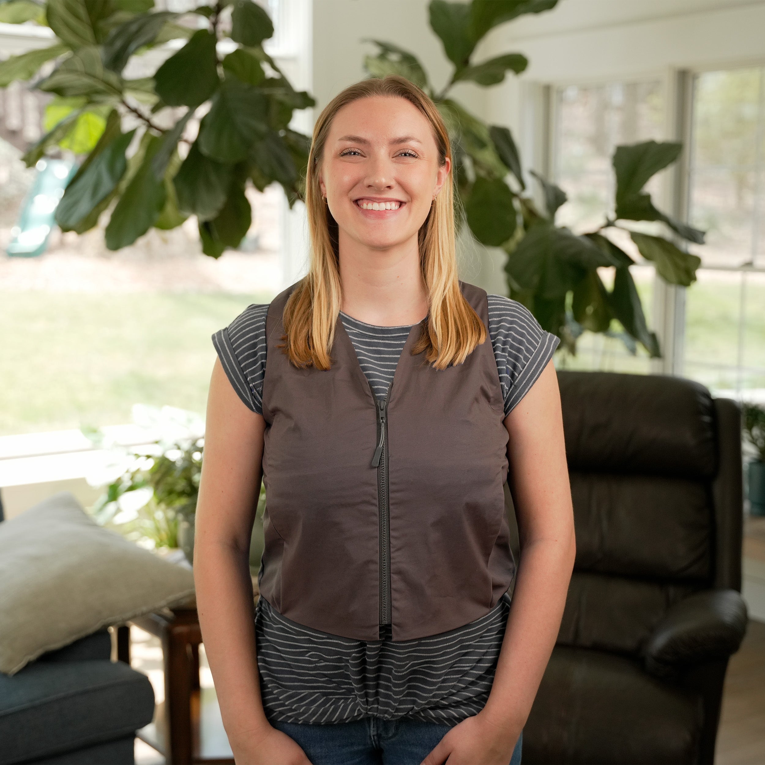 Woman standing in a living room wearing a Gray Cooling Fashion Vest with Kool Max® packs