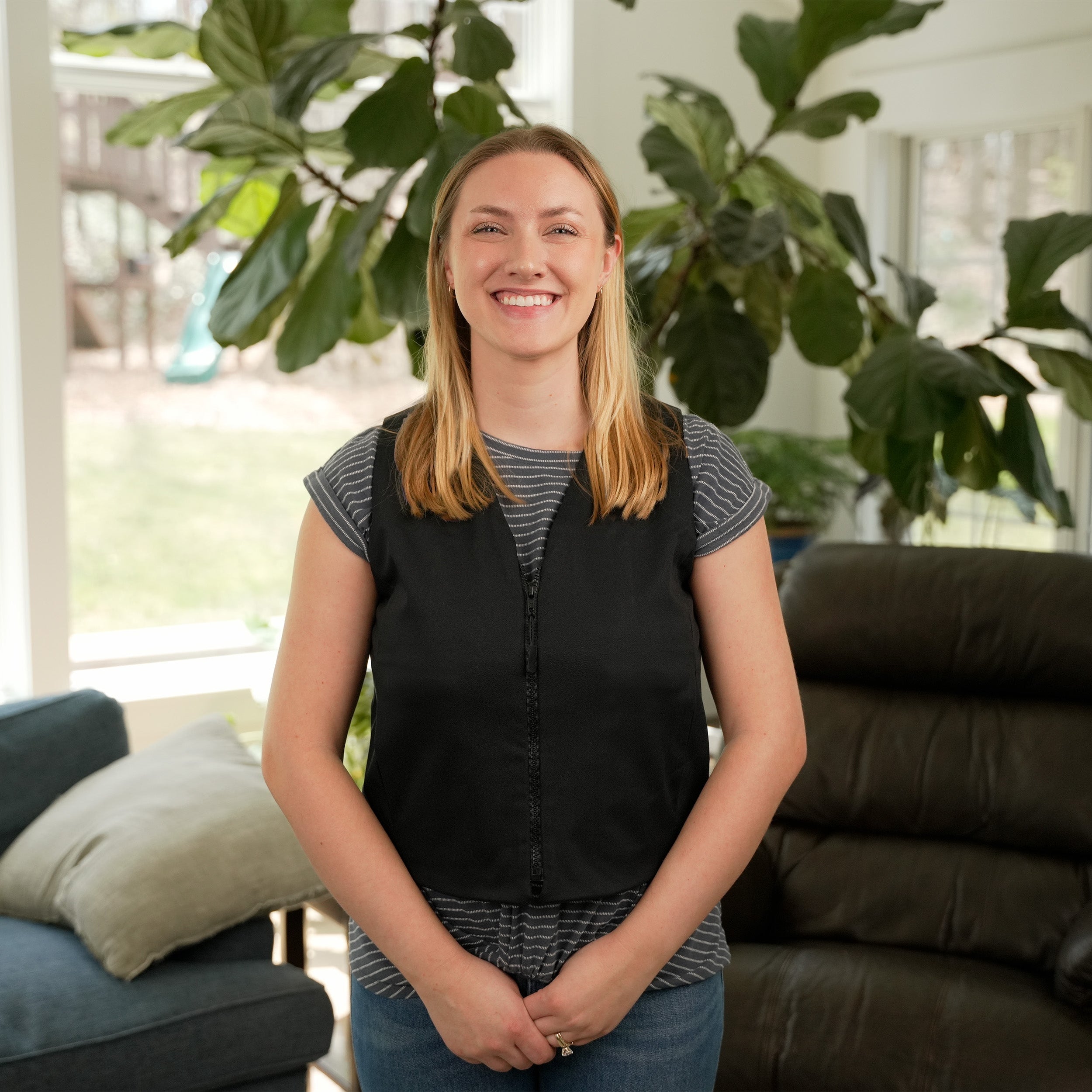 Woman standing in a living room wearing a Black Cooling Fashion Vest with Kool Max® packs