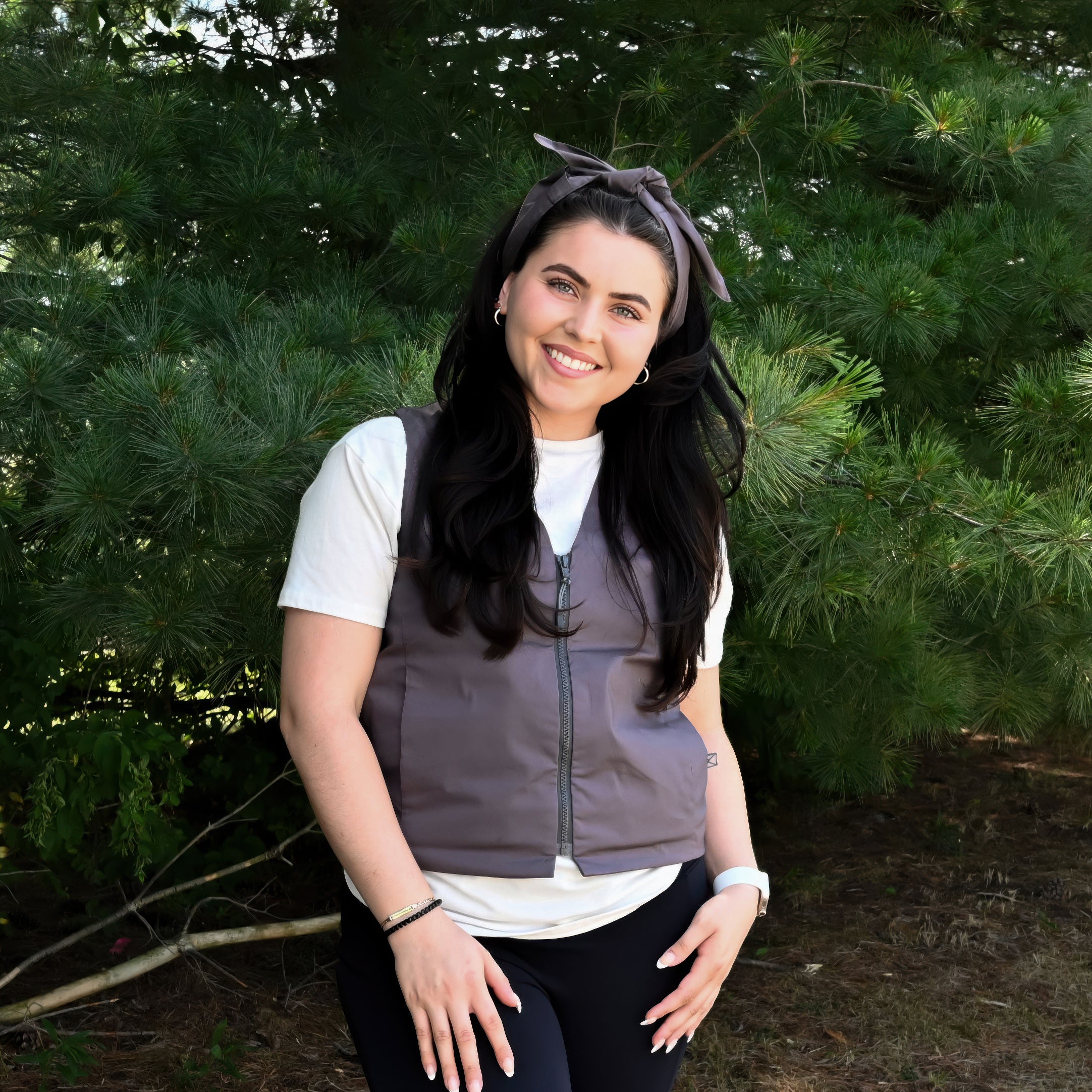 Woman outside in front of a green tree wearing a gray fashion cooling vest and a matching gray deluxe cooling neck wrap