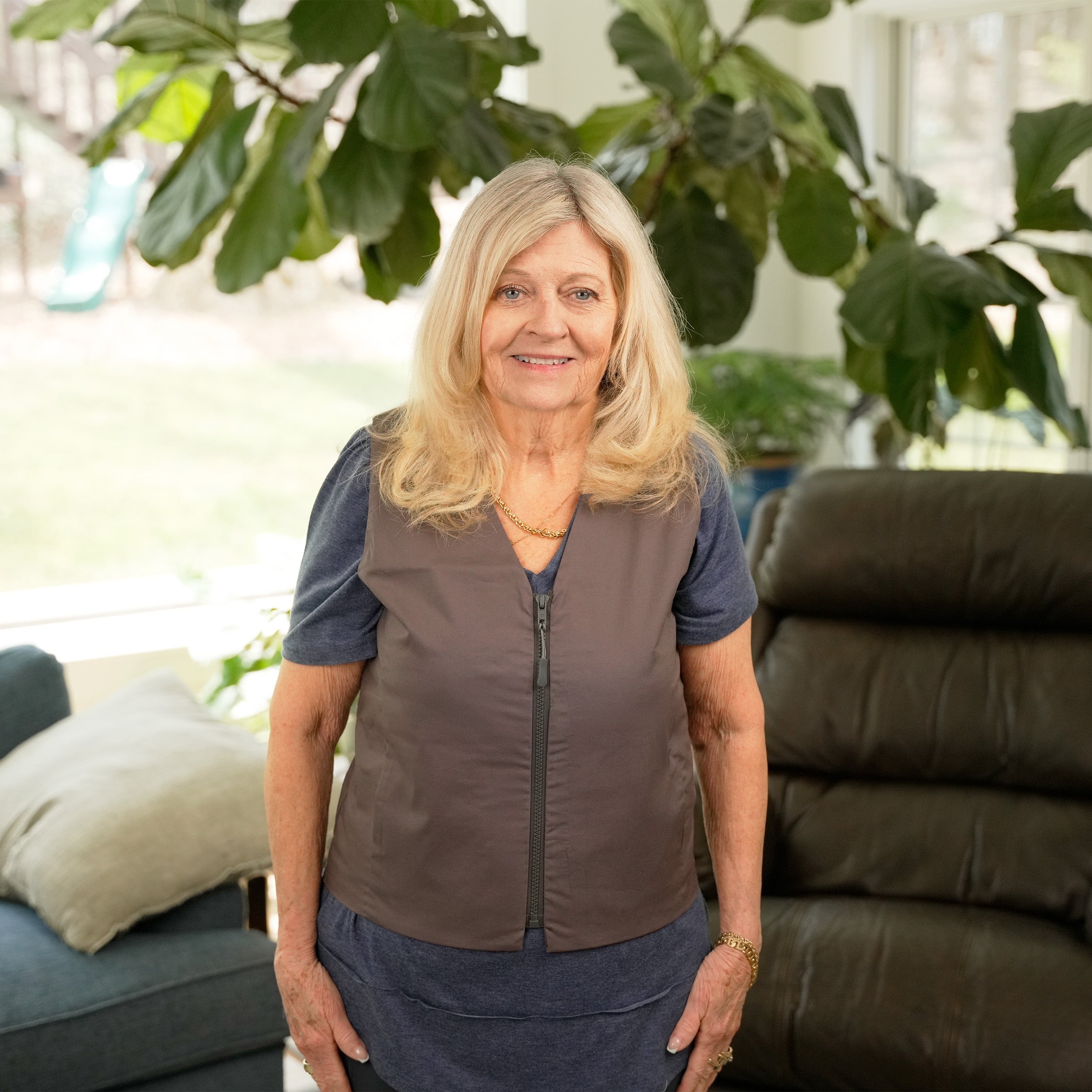 Woman standing in a living room wearing a Gray Cooling Fashion Vest with Cool58® packs