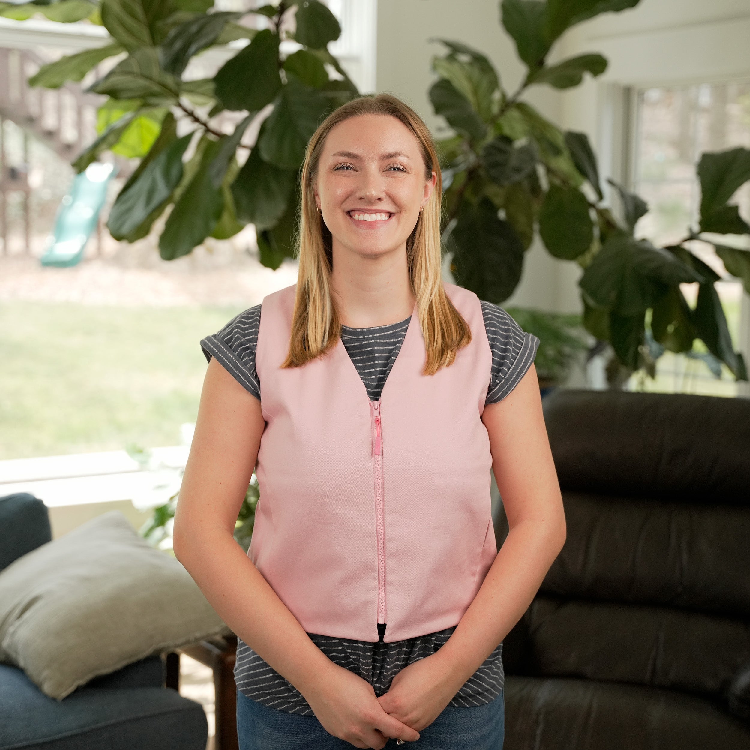 Woman standing in a living room wearing a Pink Cooling Fashion Vest with Kool Max® packs