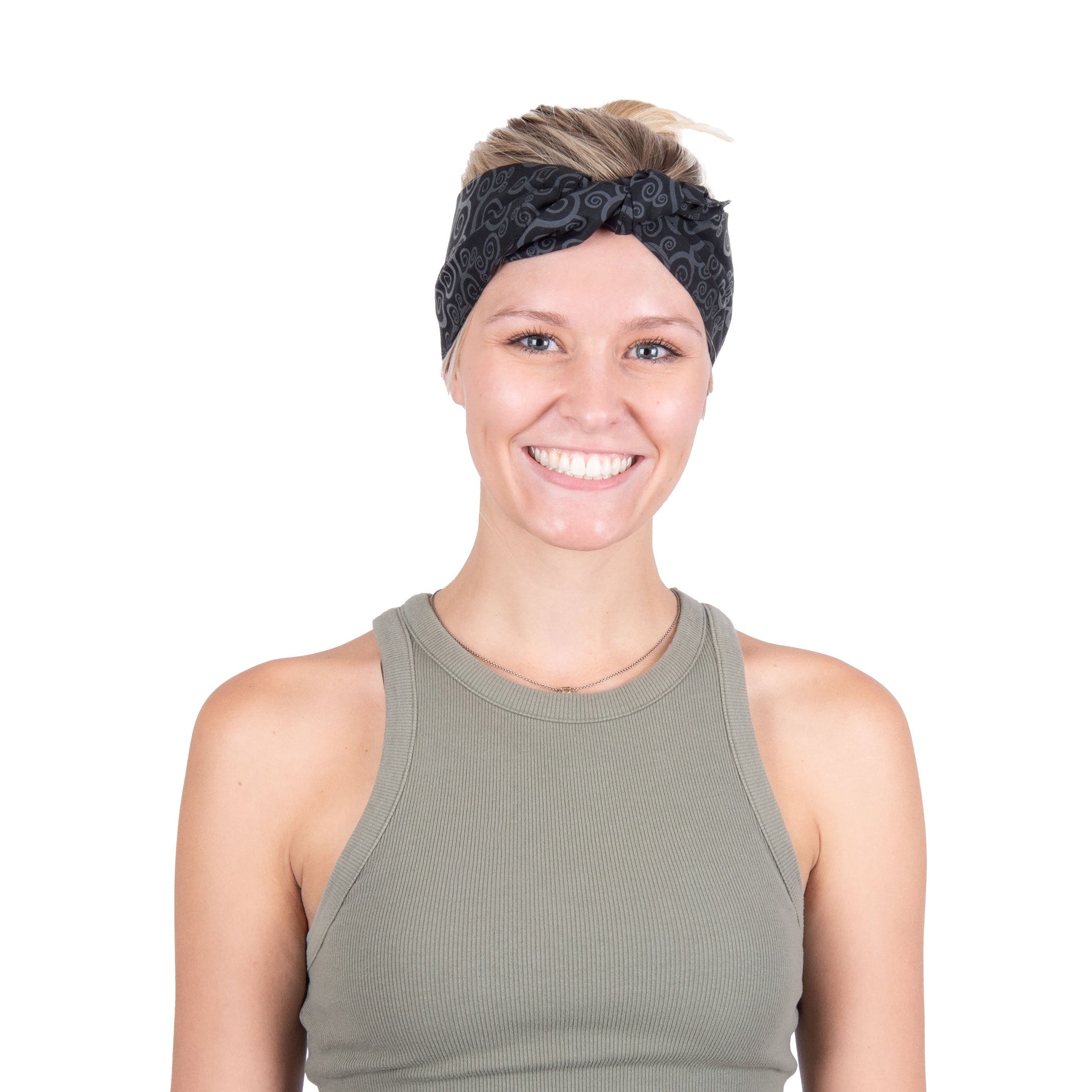 A smiling woman with short blonde hair wearing a black patterned Cooling Head Wrap and an olive green ribbed tank top, photographed against a solid white background.