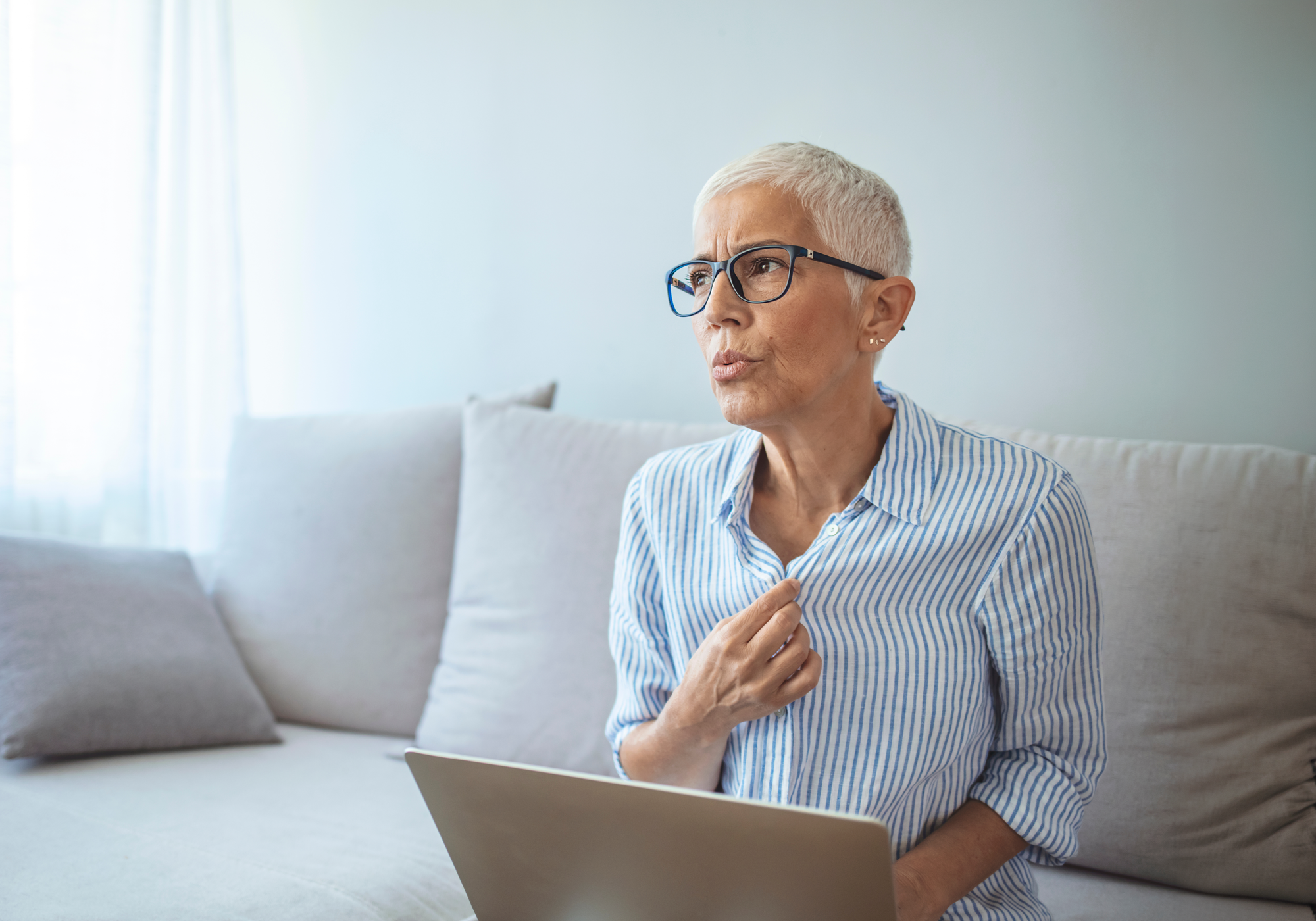 Woman sitting on a couch using a laptop in a bright room