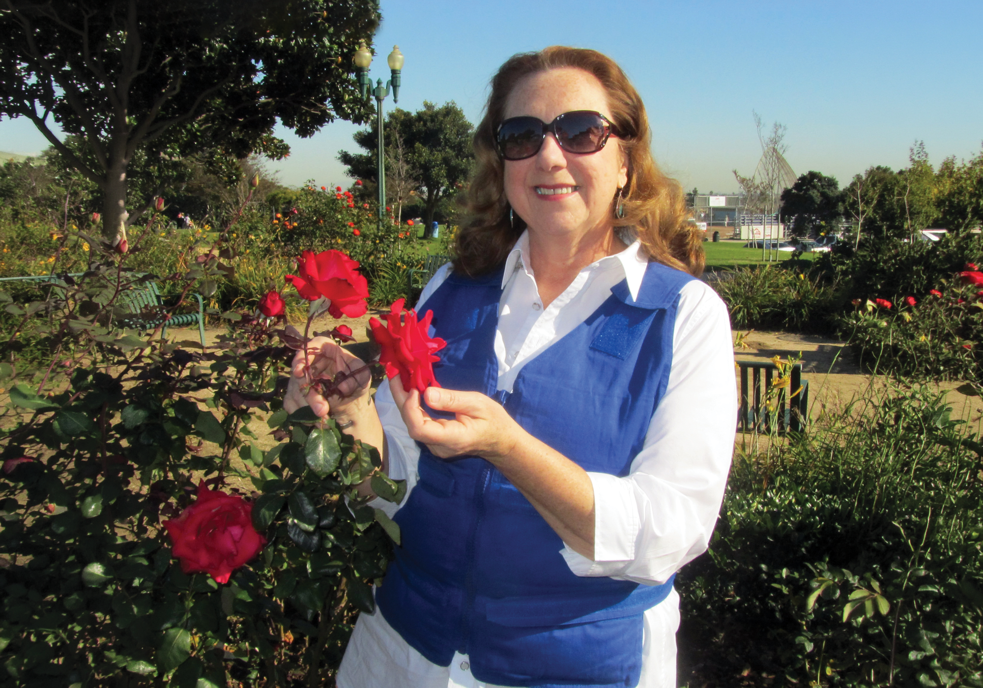 Woman holding red flowers in a garden setting