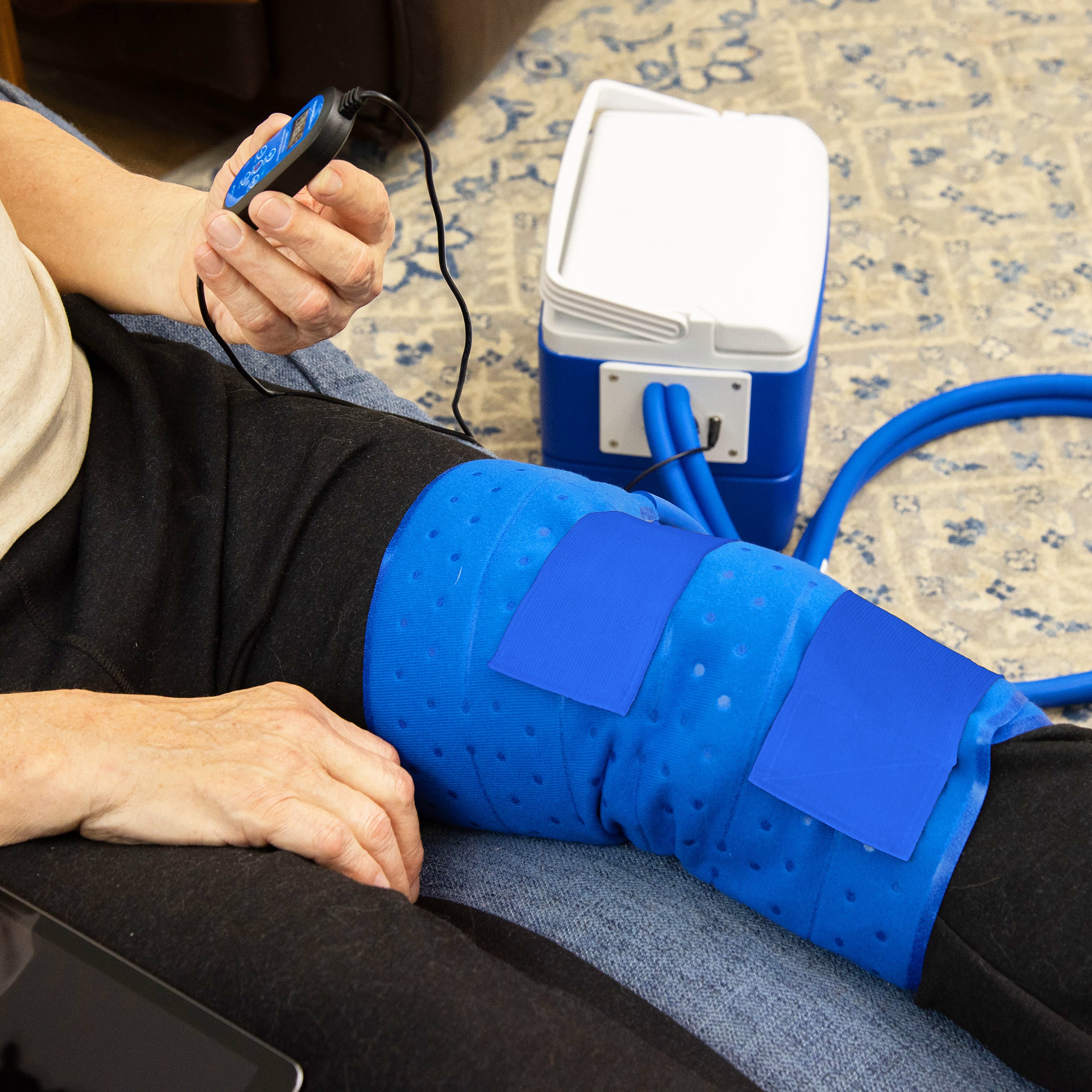 Closeup of a person using the Active Ice® Full Circumference Knee Cold Therapy System while sitting on the couch