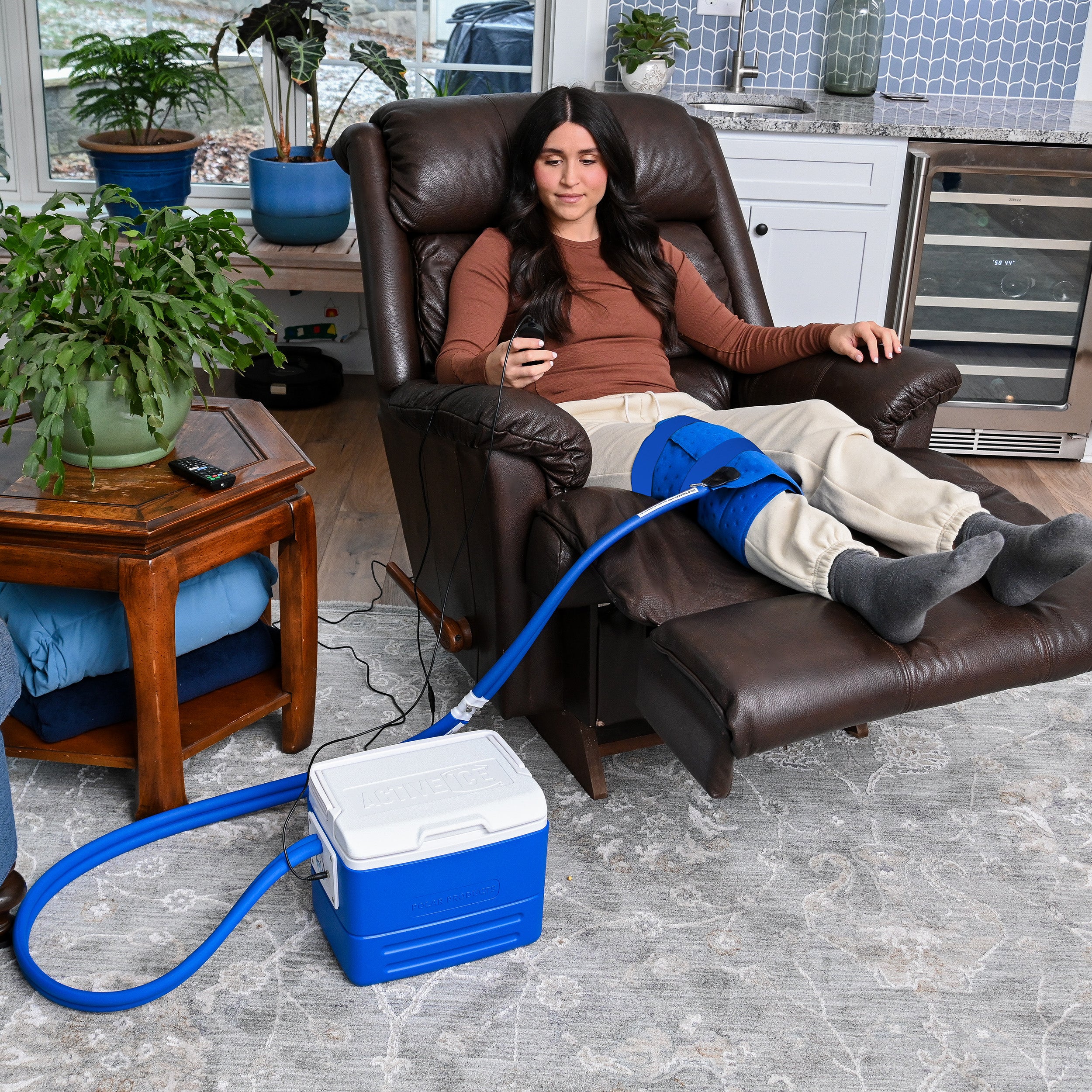 Woman sitting in a recliner with the Active Ice® Full Circumference Knee Cold therapy system