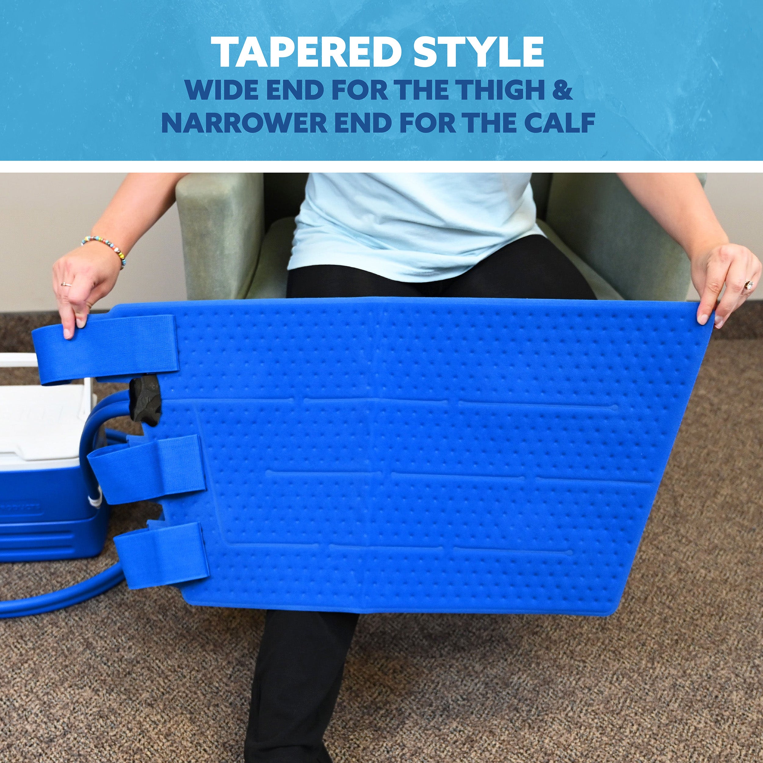 A person seated in an armchair holds a bright blue tapered full circumference knee cold therapy pad, with text at the top reading 'TAPERED STYLE' and 'WIDE END FOR THE THIGH & NARROWER END FOR THE CALF.'.
