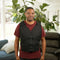 Man wearing a black Adjustable Zipper Cooling Vest with Kool Max® Packs in a bright living room with plants.