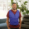Man wearing a blue Kool Max® Adjustable Zipper Cooling Vest in a bright living room with plants in the background.