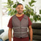 Man wearing a gray Adjustable Zipper Cooling Vest with Kool Max® packs over a red shirt in a living room setting with plants and furniture.