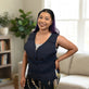 A woman with purple hair is wearing a navy blue waist Adjustable Zipper Cooling Vest in nylon in a brightly lit living room setting.