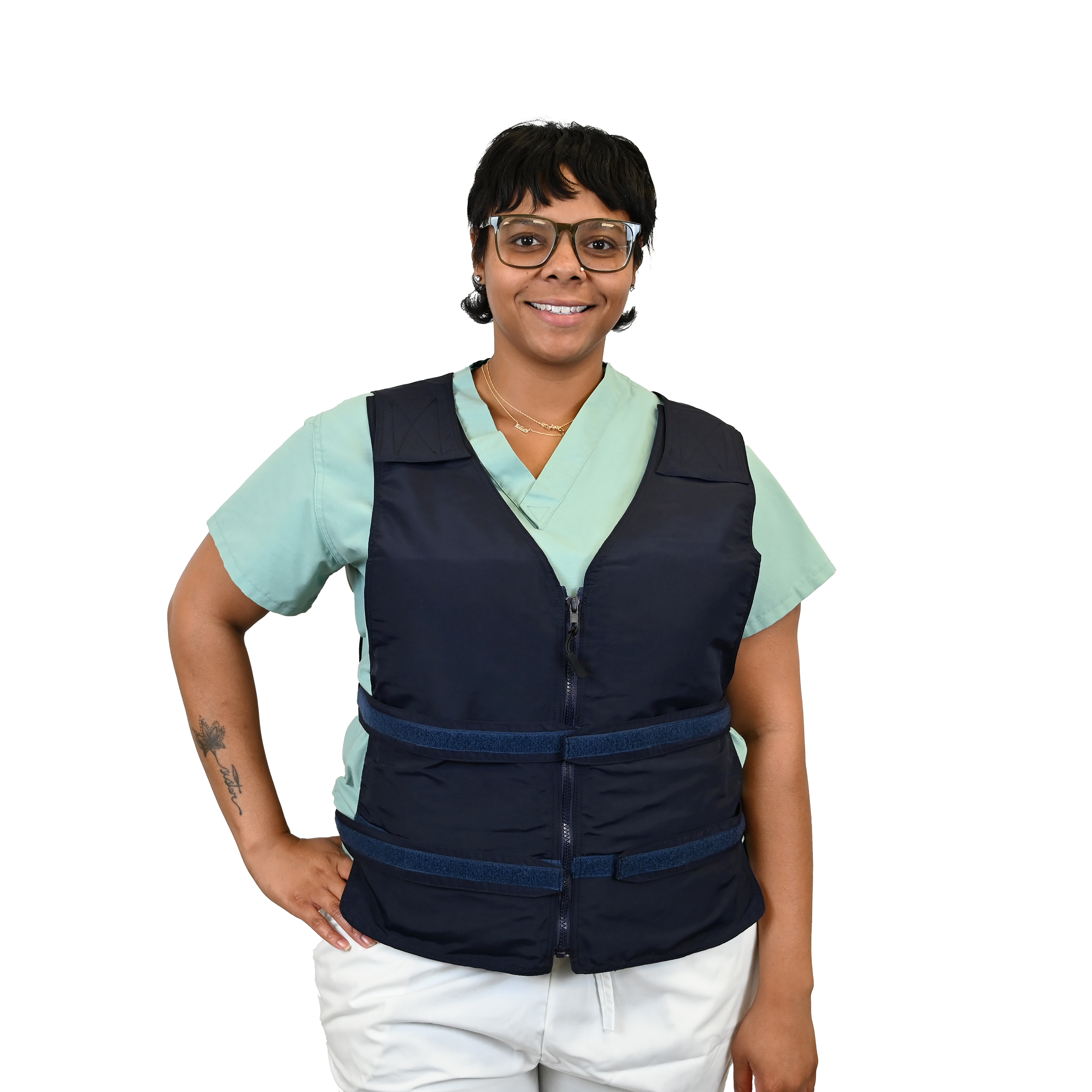 A woman wearing a navy blue nylon adjustable cooling vest over mint green scrubs and white pants, standing against a solid white background.