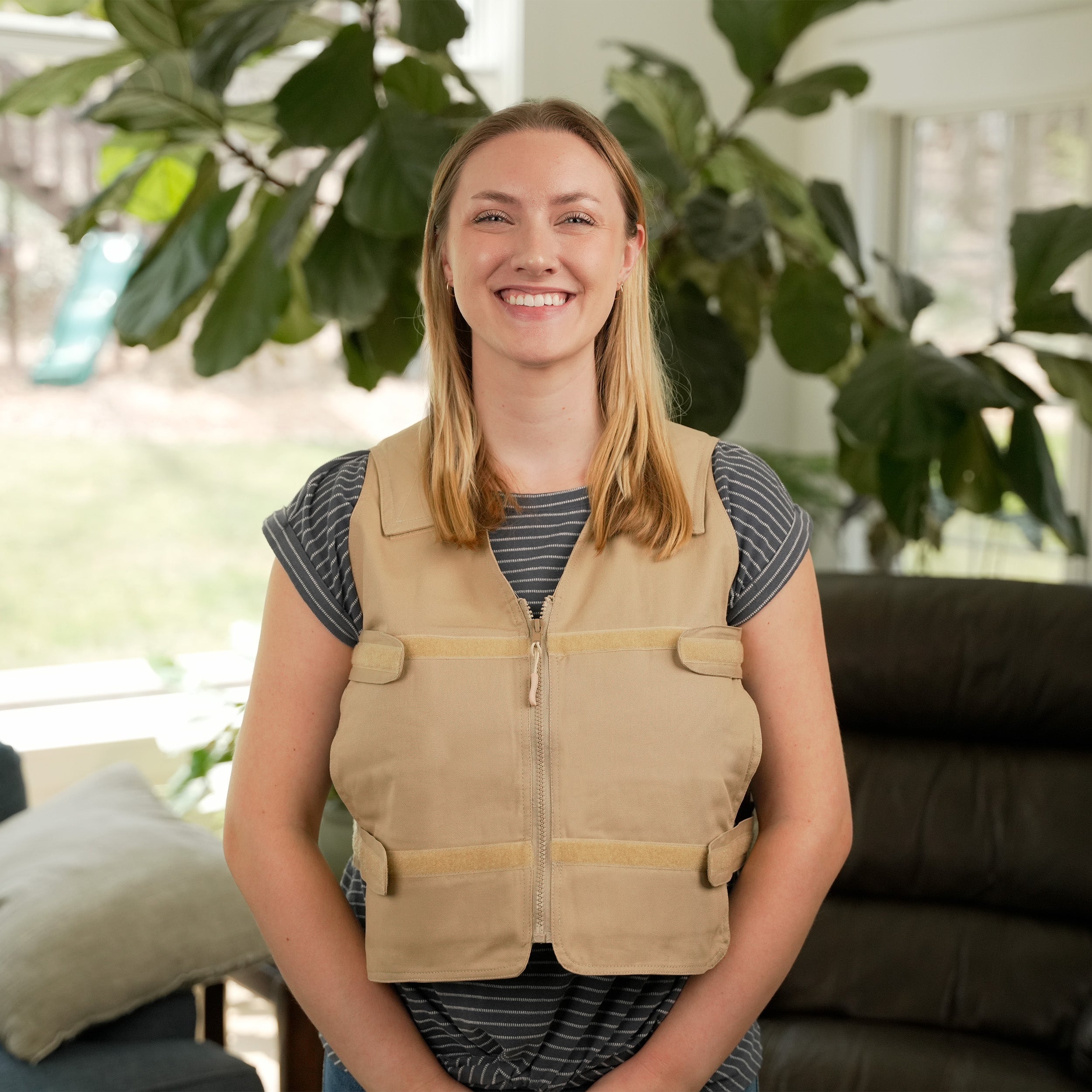 Woman wearing a khaki Adjustable Zipper Cooling Vest with Kool Max® Packs in a bright living room with plants in the background.