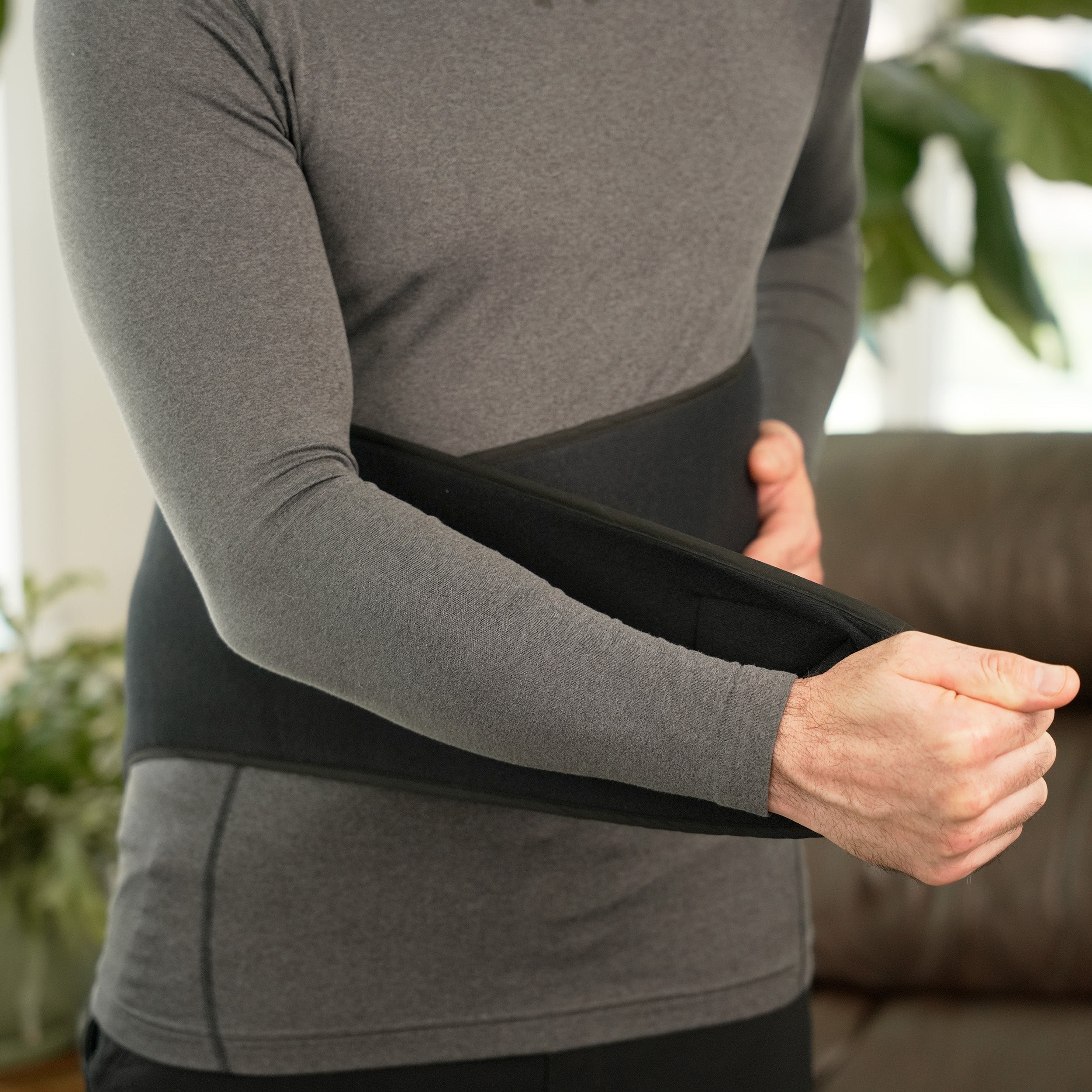 Person wearing a gray shirt and applying a Soft Ice® Lumbosacral Wrap on lower back.