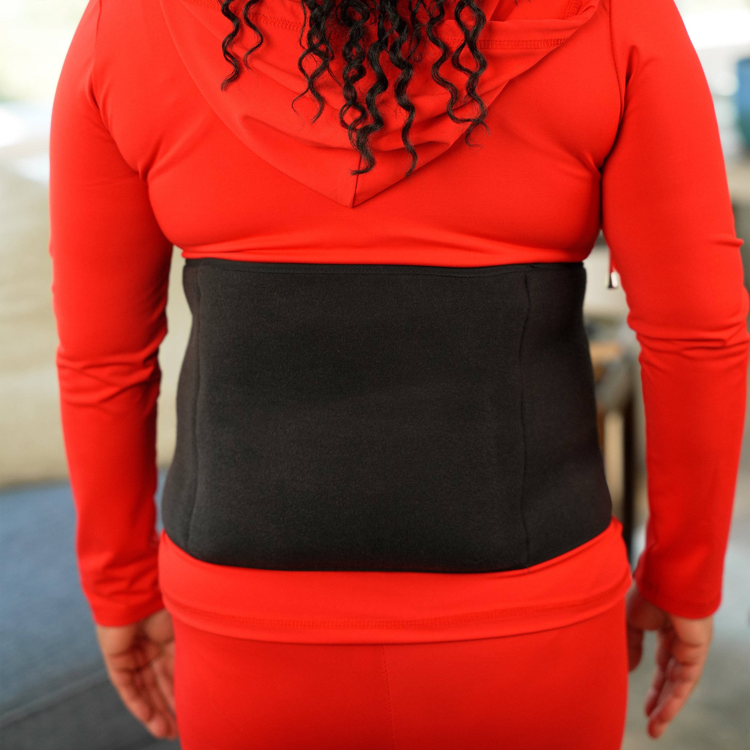 Woman wearing a red outfit with a black Soft Ice® Back & Hip Wrap.