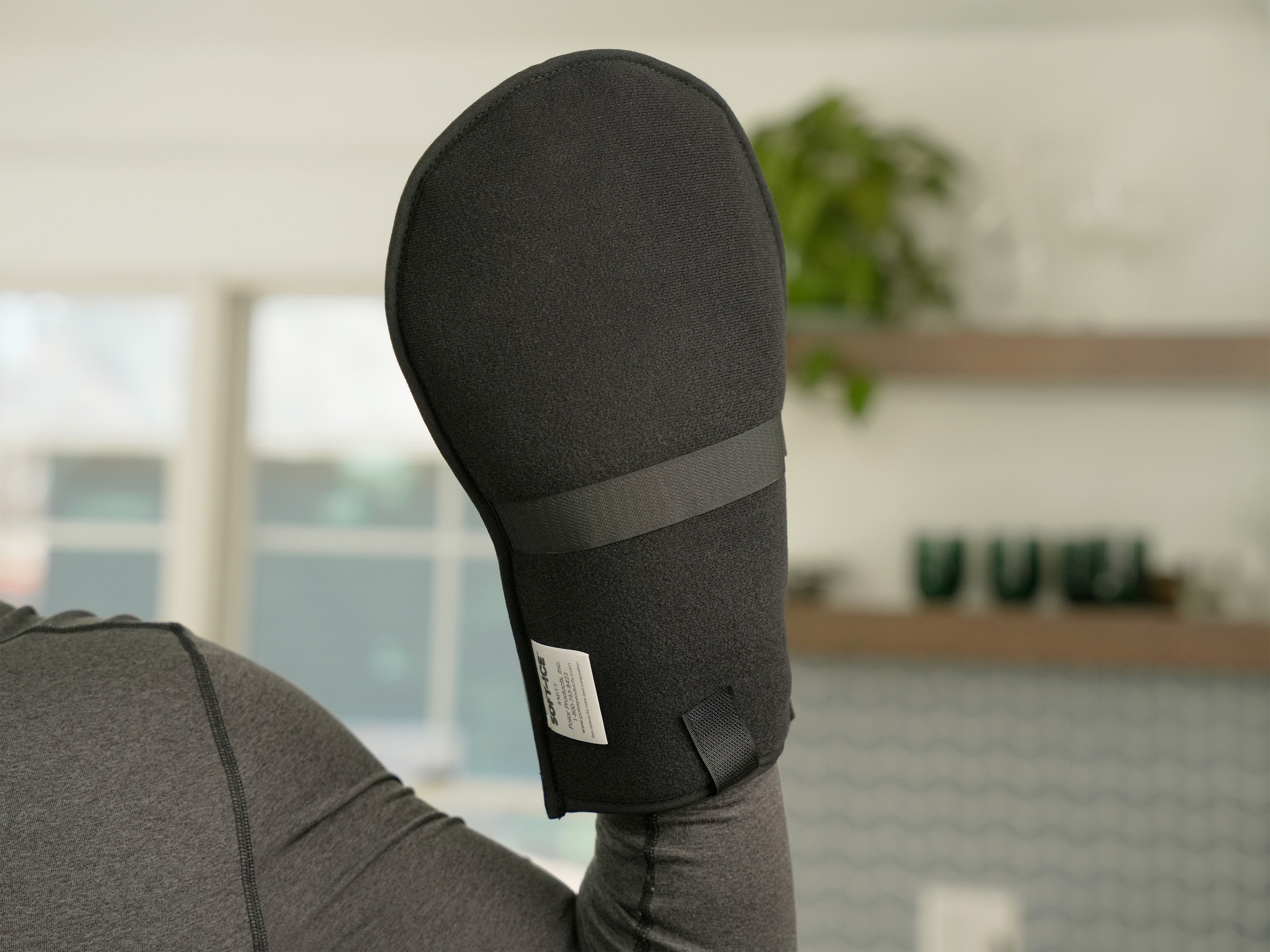 Man wearing a gray long-sleeve shirt with a black Soft Ice® Mitt on his hand in a home setting.