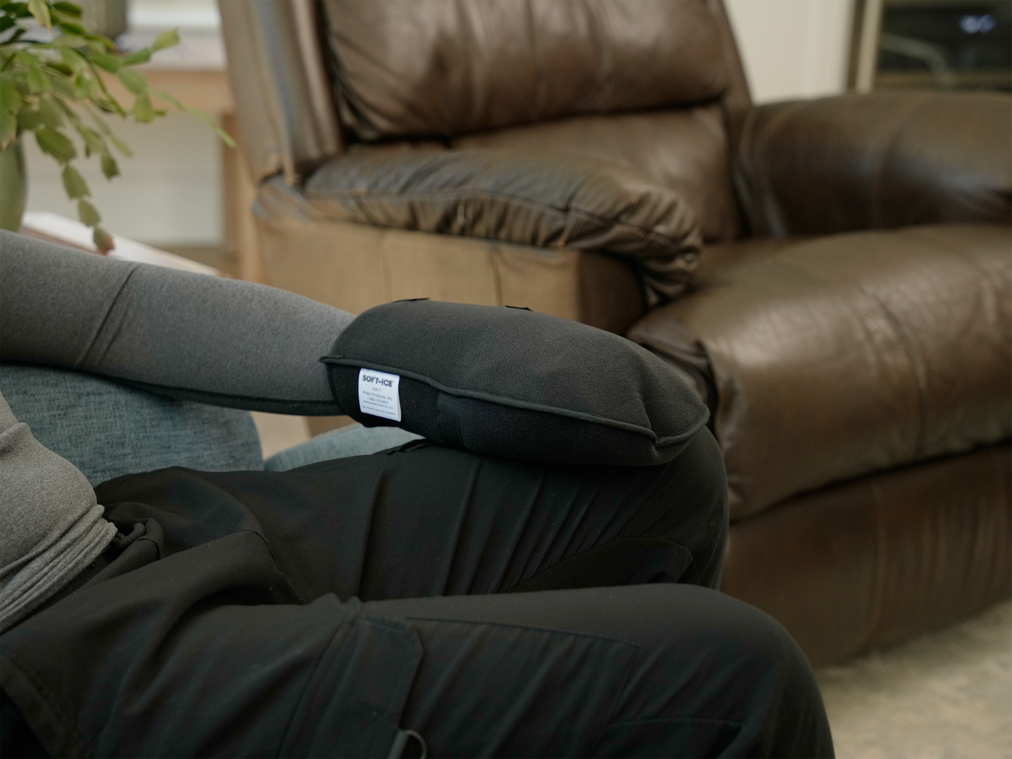 Man wearing a gray long-sleeve shirt with a black Soft Ice® Mitt on his hand in a home setting.
