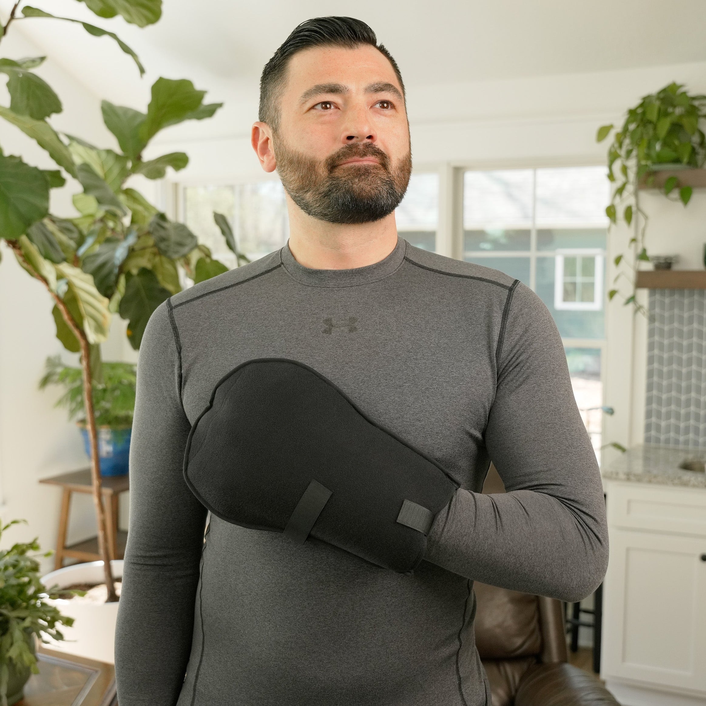 Man wearing a gray long-sleeve shirt with a black Soft Ice® Mitt on his hand in a home setting.