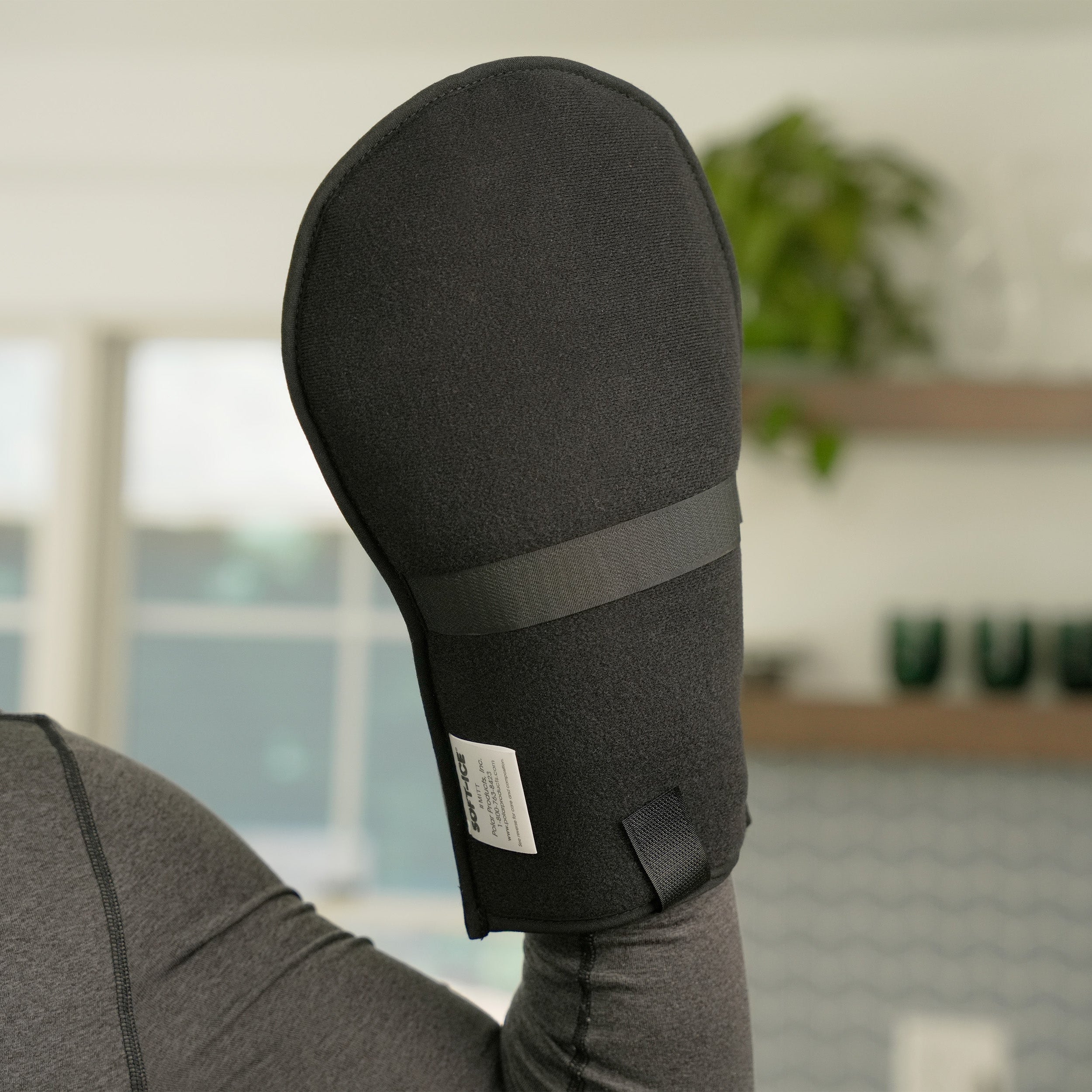 Man wearing a gray long-sleeve shirt with a black Soft Ice® Mitt on his hand in a home setting.