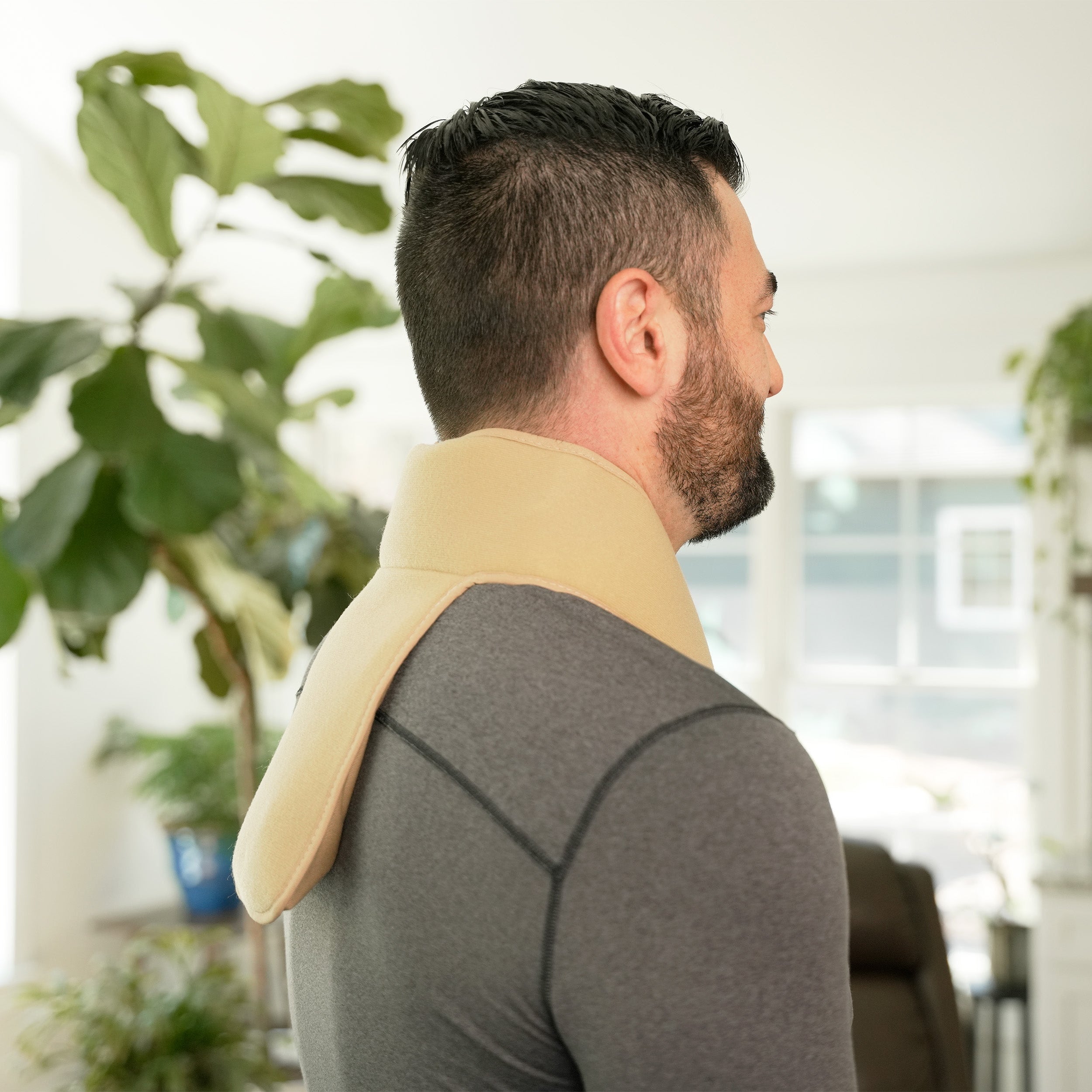 Man wearing a Khaki Soft Ice® Neck & Upper Spine Wrap in a home setting