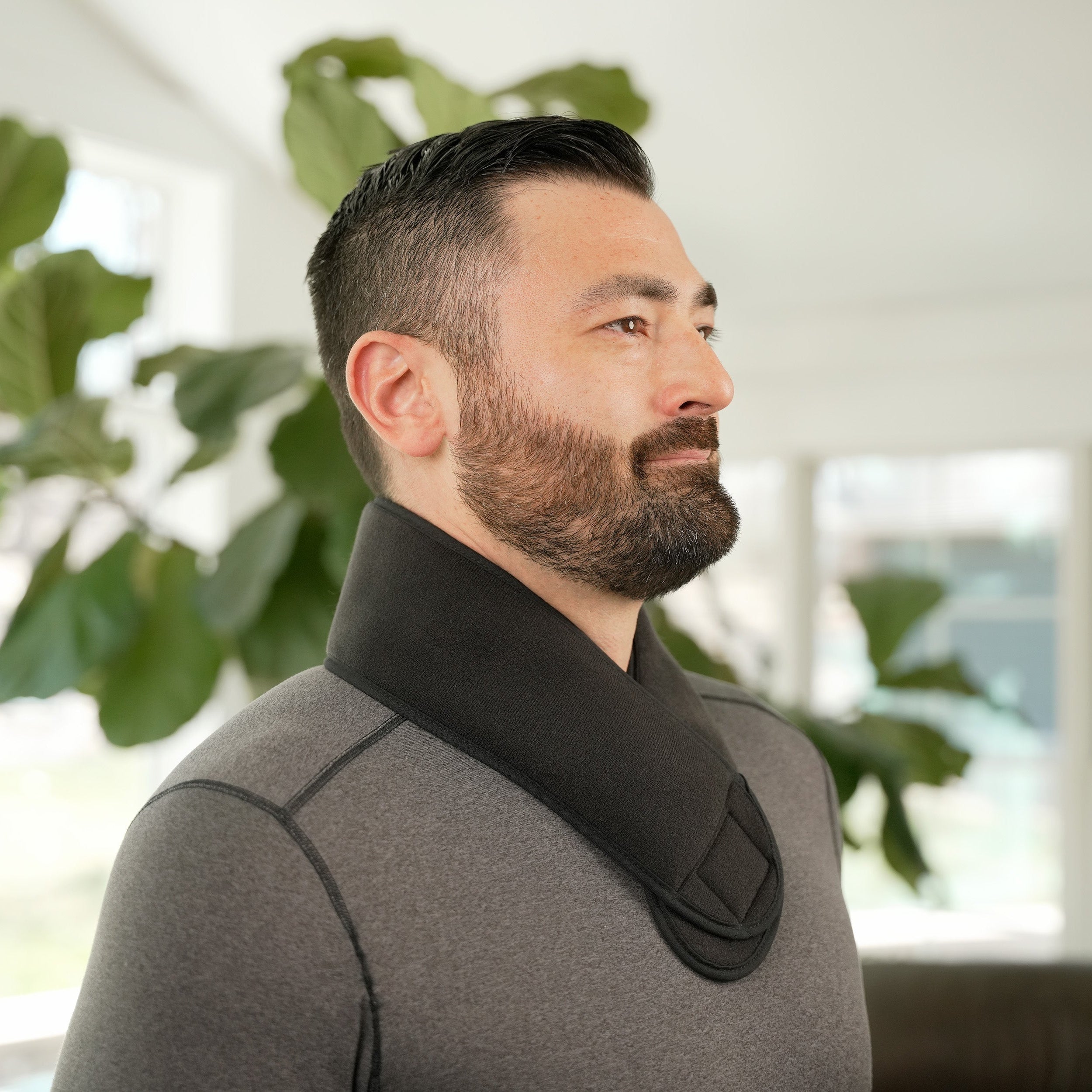 Man wearing a Soft Ice® Neck and Head Wrap in a home setting with plants in the background