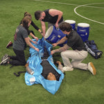 Person with heat illness laying in portable Polar Life Pod® with people holding it open and pouring in ice-water from 10 gallon container on a grassy field.