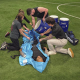Person with heat illness laying in portable Polar Life Pod® with people holding it open and pouring in ice-water from 10 gallon container on a grassy field.