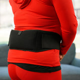 Person wearing a red outfit with a black Soft Ice® Standard Universal Compression Wrap on her back in an indoor setting.