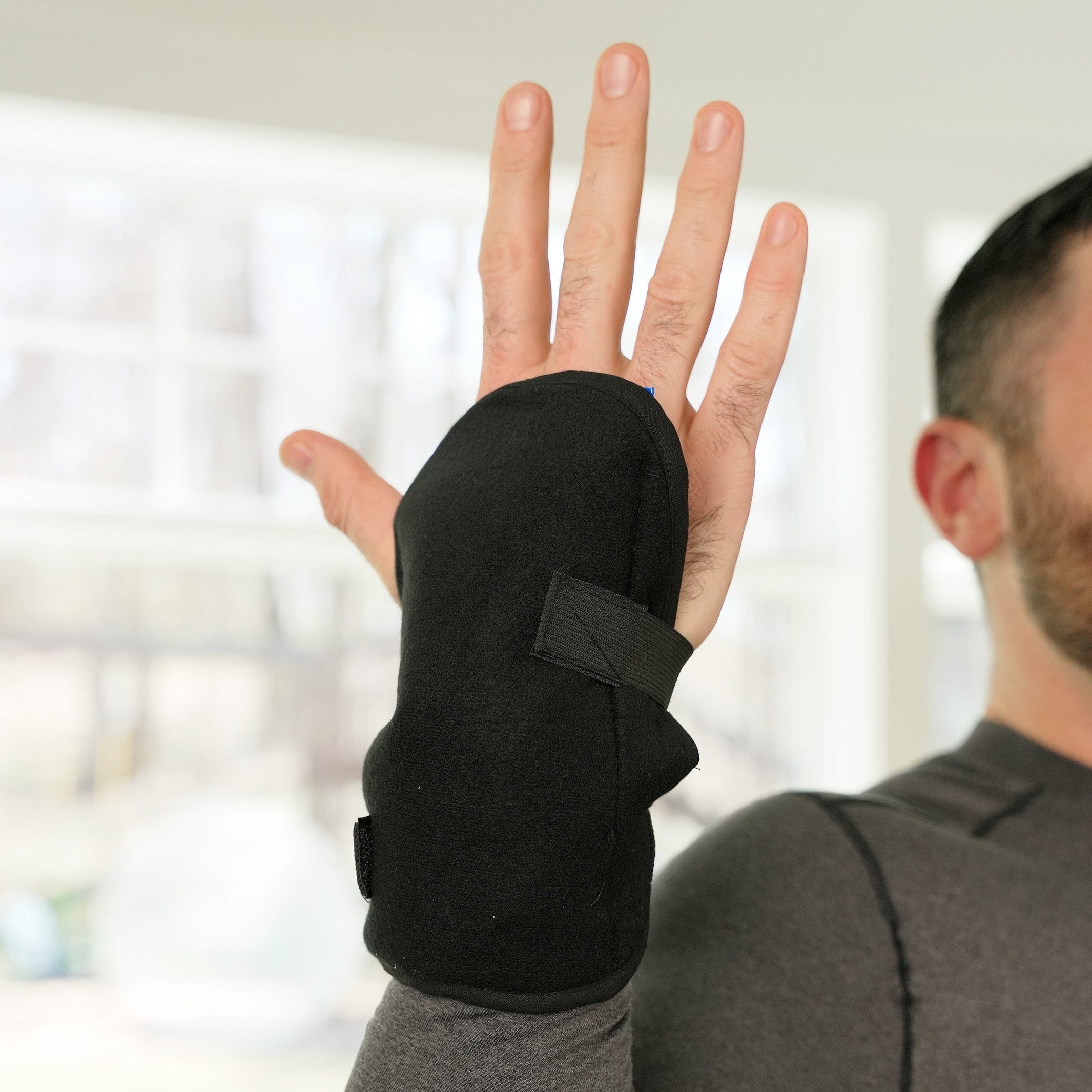 Person wearing a black Soft Ice® Wrist Wrap indoors