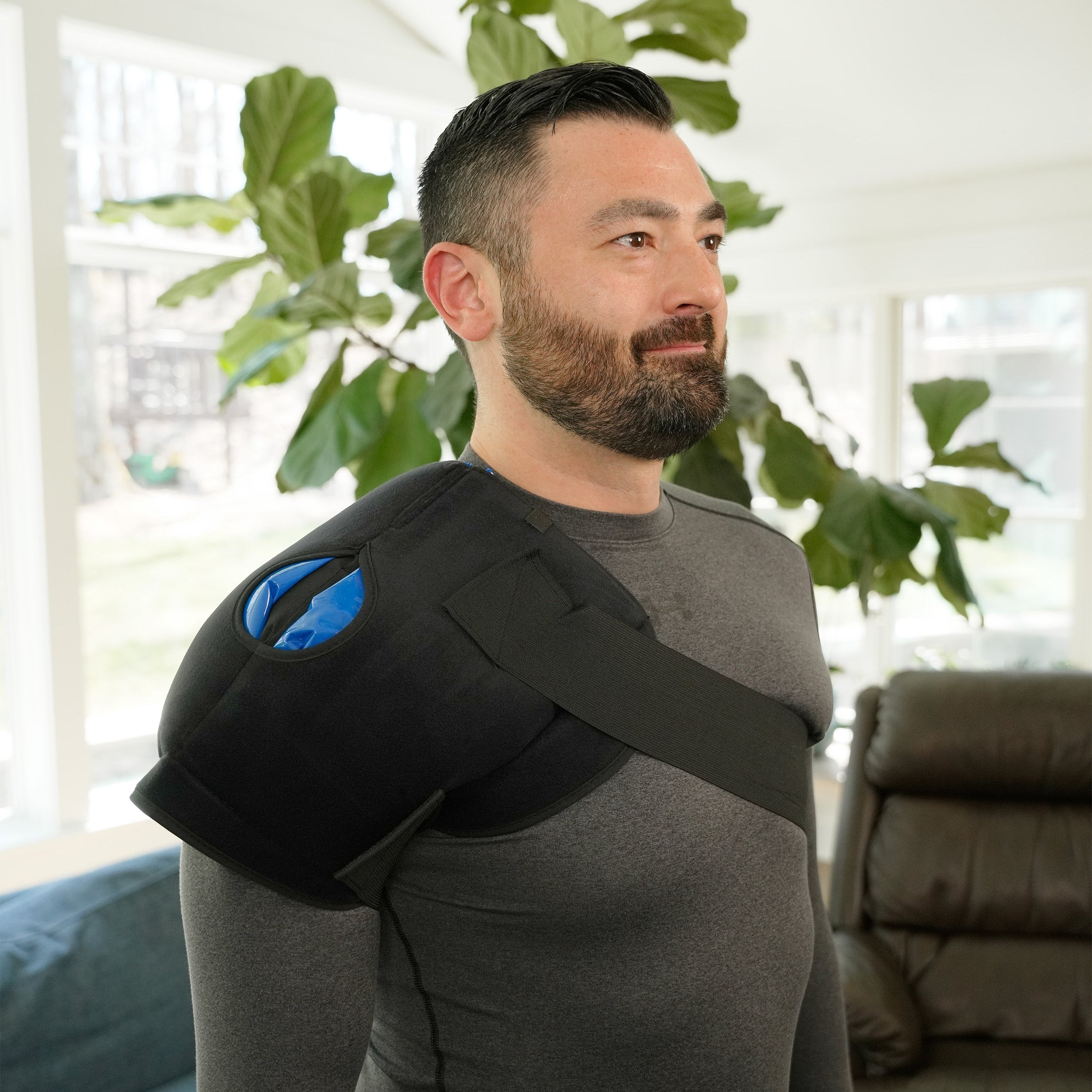 Man wearing a black Soft Ice® Shoulder Wrap in a living room setting