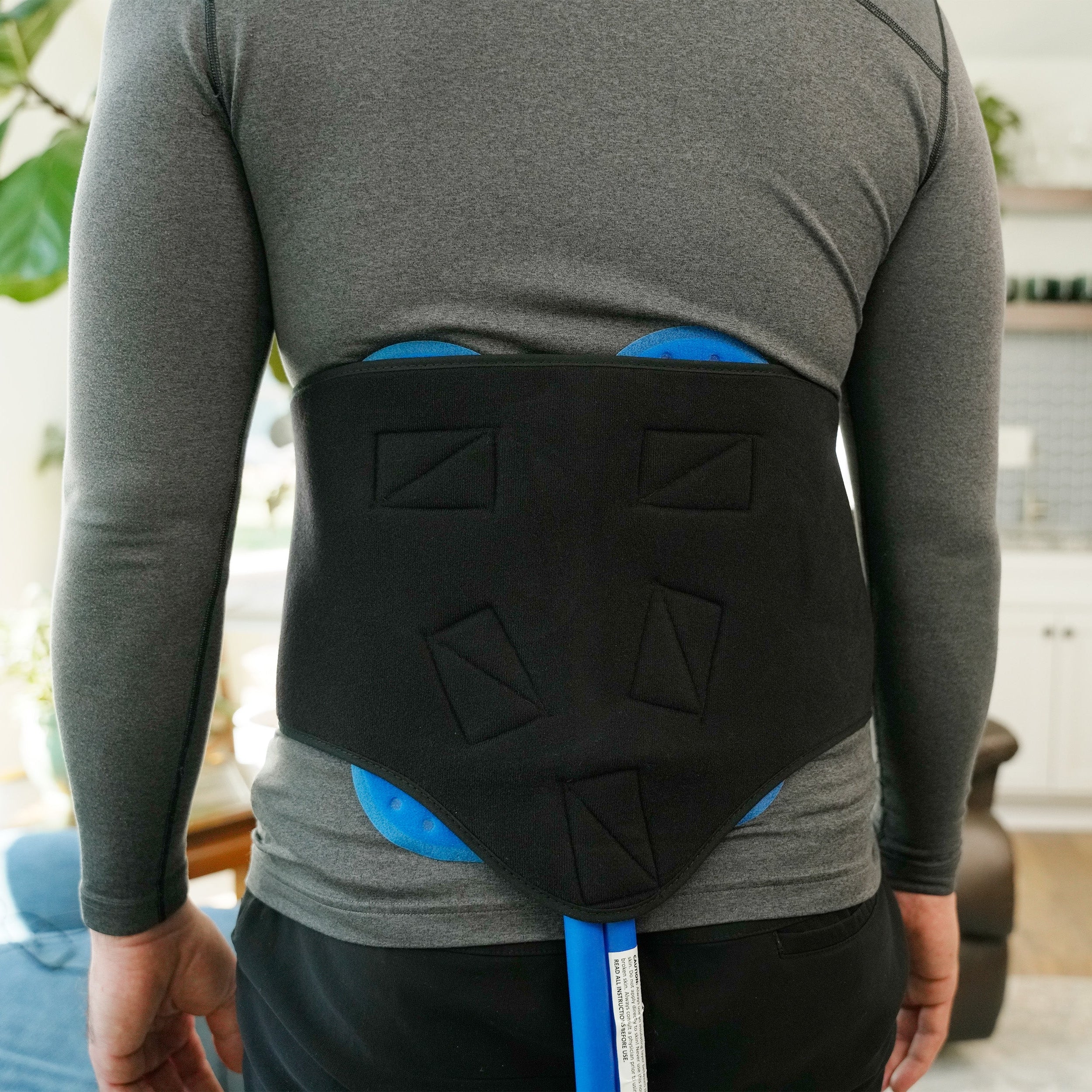 Man wearing a Active Ice® 3.0 Back or Hip Compression Wrap on his lower back in a home setting.