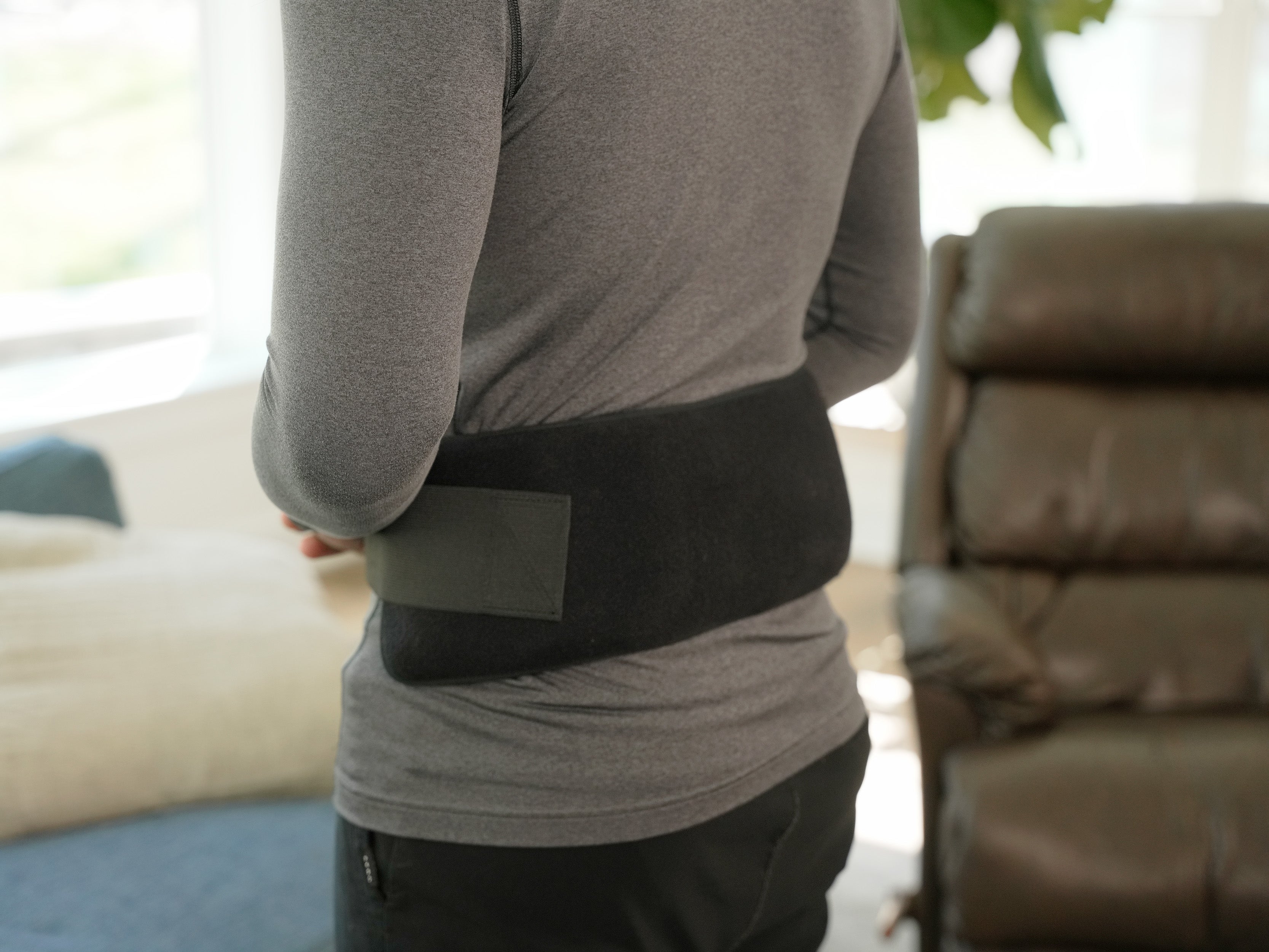 Man wearing a Soft Ice® Double Universal Compression Wrap on his back in a blurred living room setting.