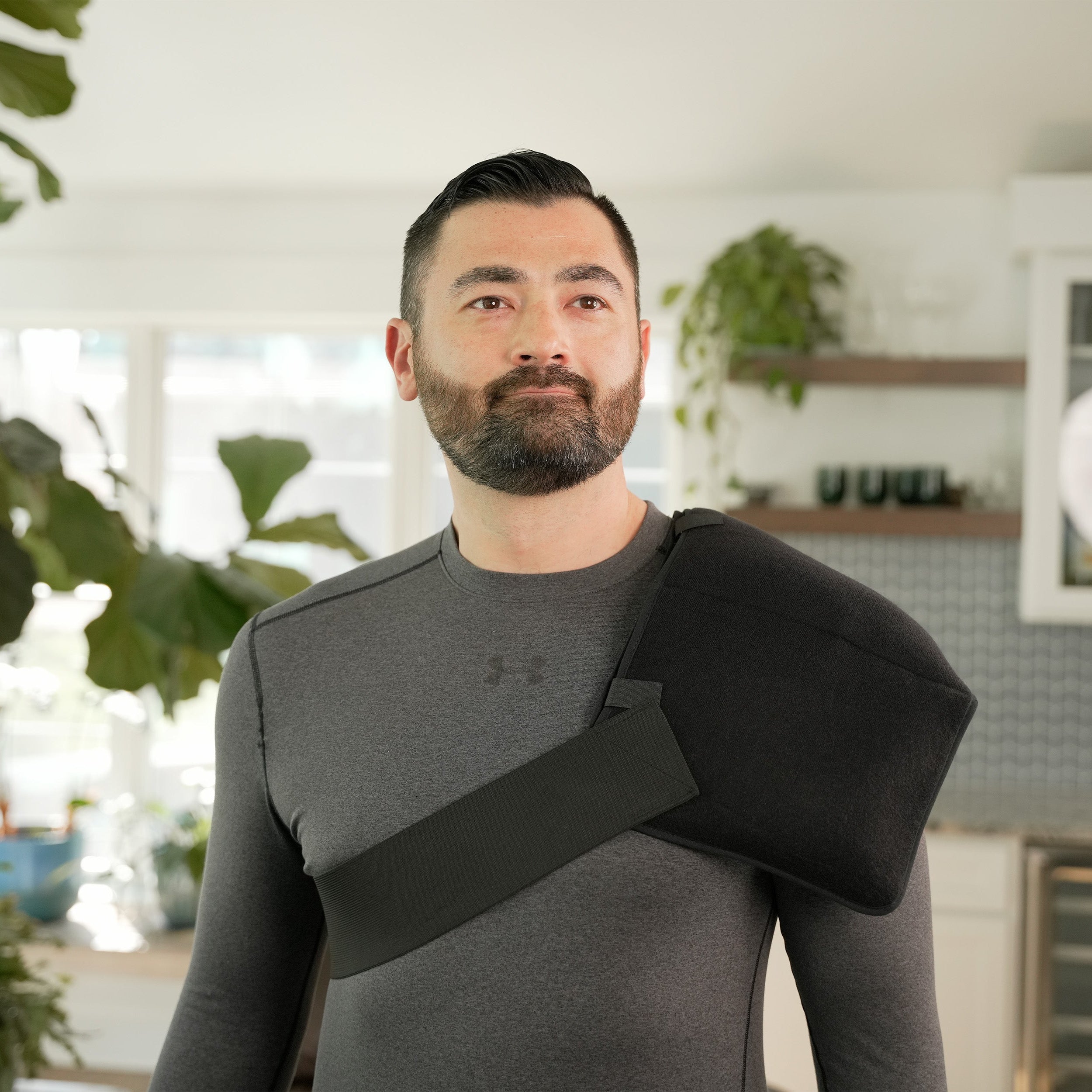 Man wearing a black Soft Ice® Triple Universal Compression Wrap on his shoulder in a kitchen setting