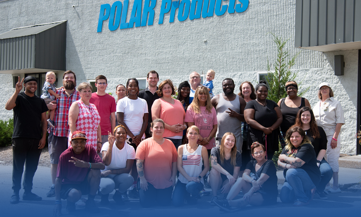 Group of people posing in front of a building with 'Polar Products' signage.